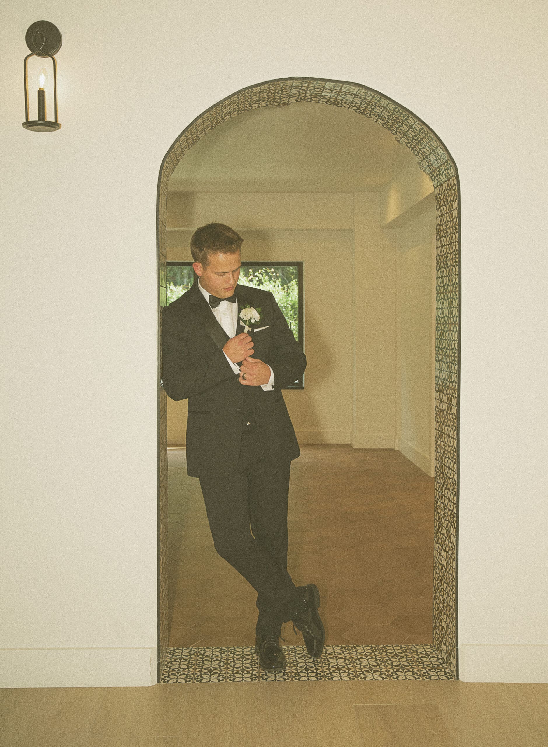 Groom adjusting his suit jacket in an arched doorway, photographed during intentional portrait time built into the wedding timeline. 