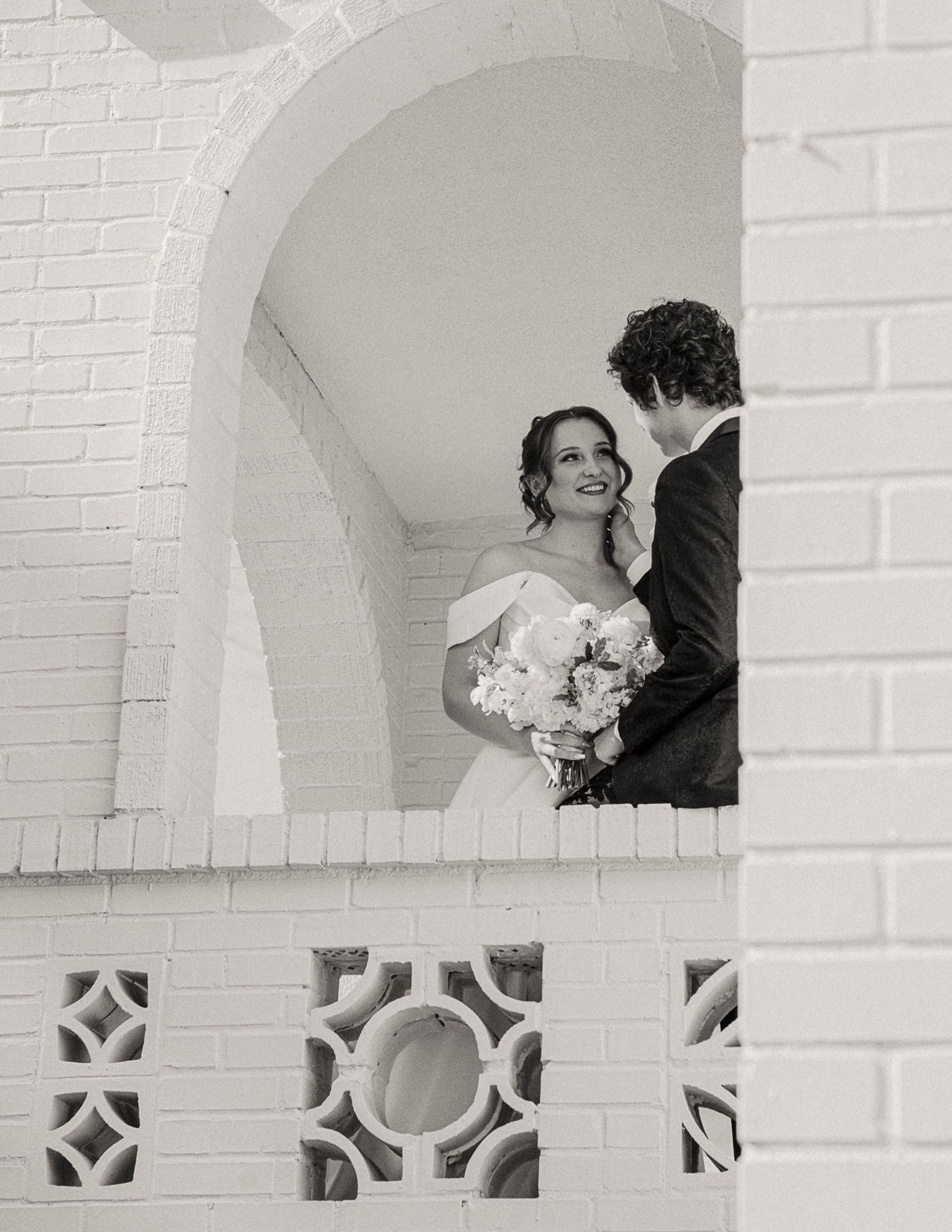 Bride and groom sharing an intimate moment framed by white brick architecture, photographed without rush thanks to a thoughtfully planned timeline. 