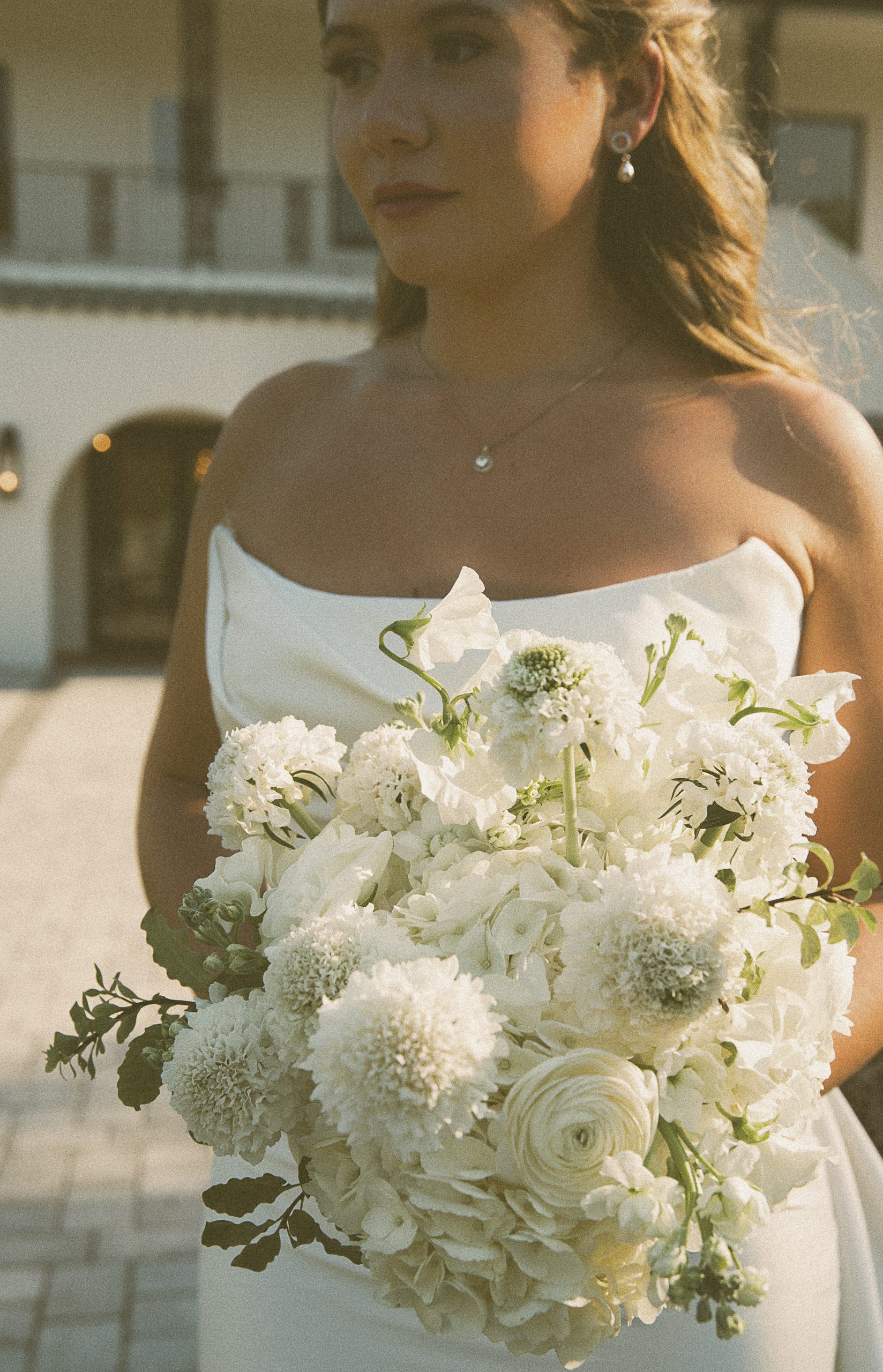 Editorial bridal portrait of a bride holding a white garden bouquet in warm afternoon light.