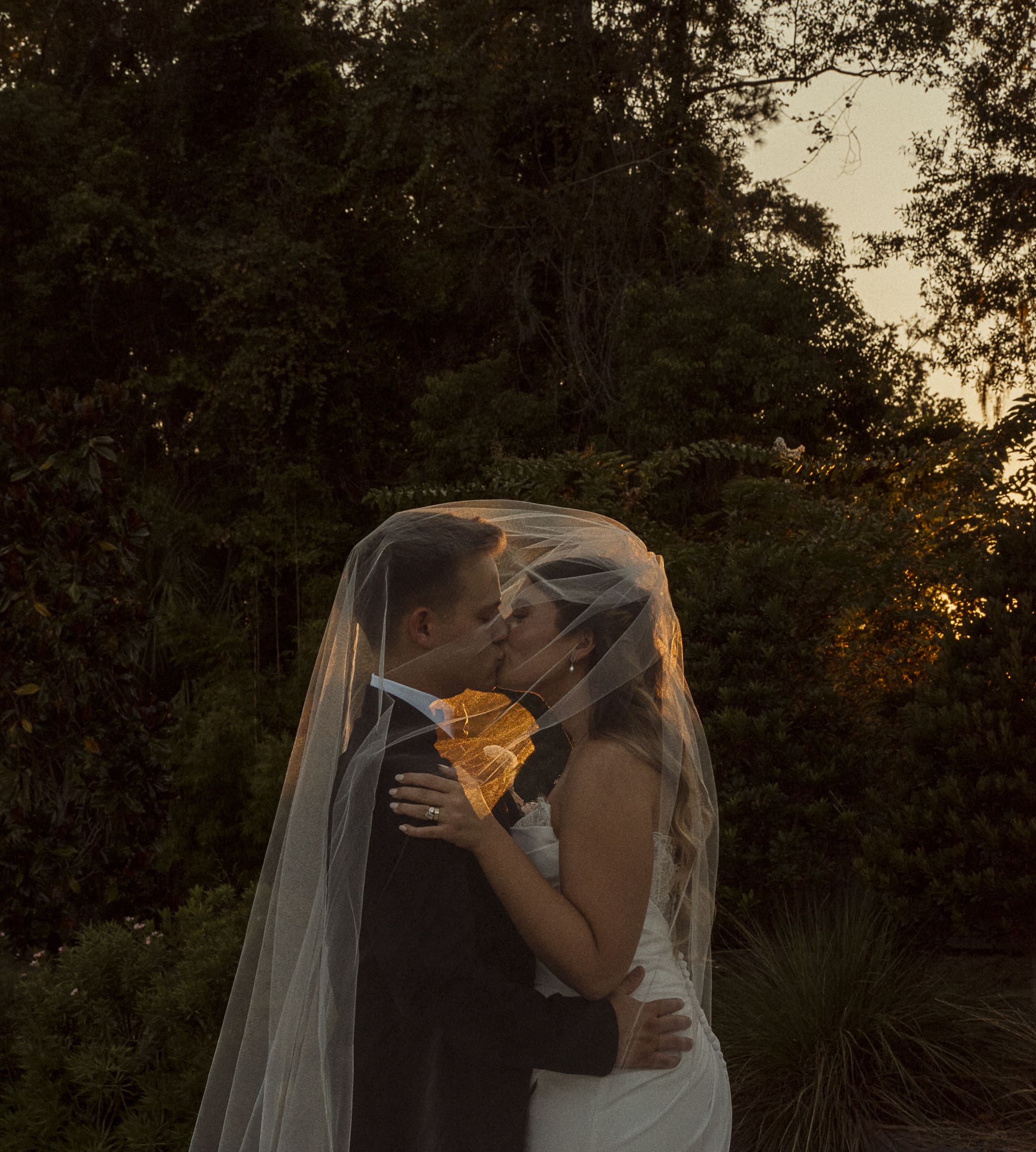 Romantic St. Augustine wedding portrait of a couple kissing under a veil at sunset during golden hour.