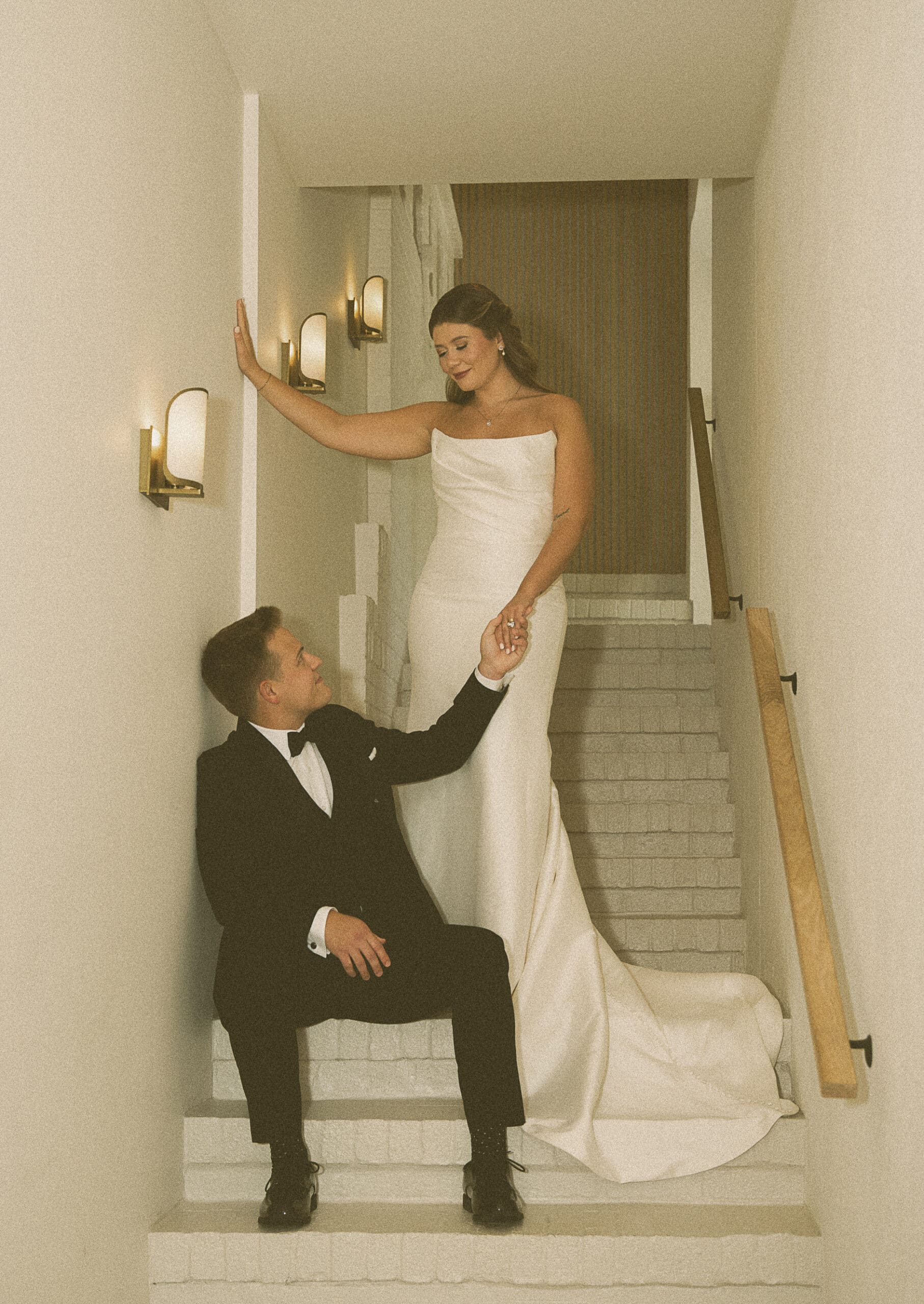 Editorial-style wedding portrait featuring a bride and groom posed on a modern staircase, highlighting elegant composition and intentional artistry.