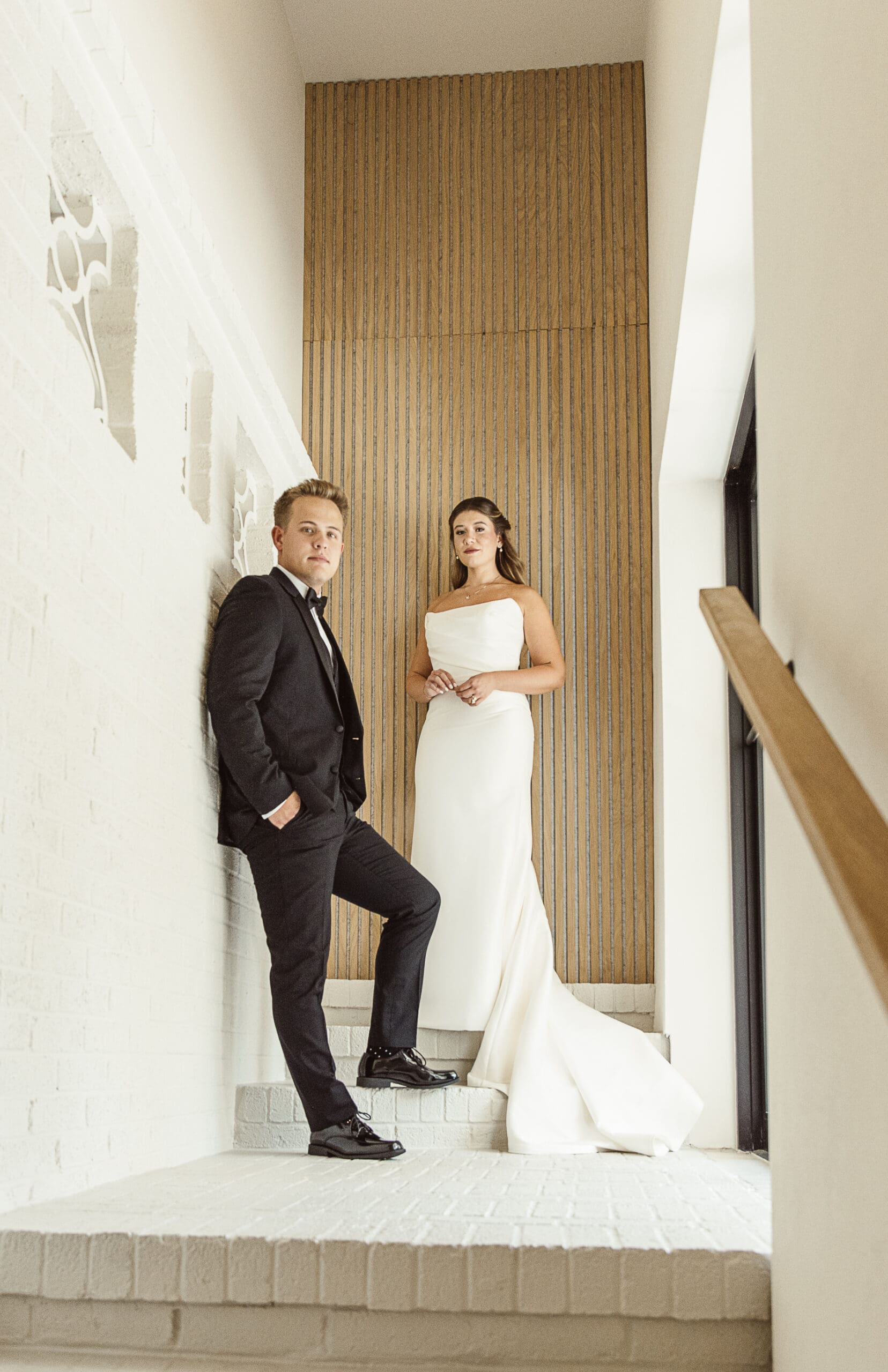 Bride and groom standing in a minimalist architectural space, photographed with intentional composition to allow breathing room in the wedding day timeline.