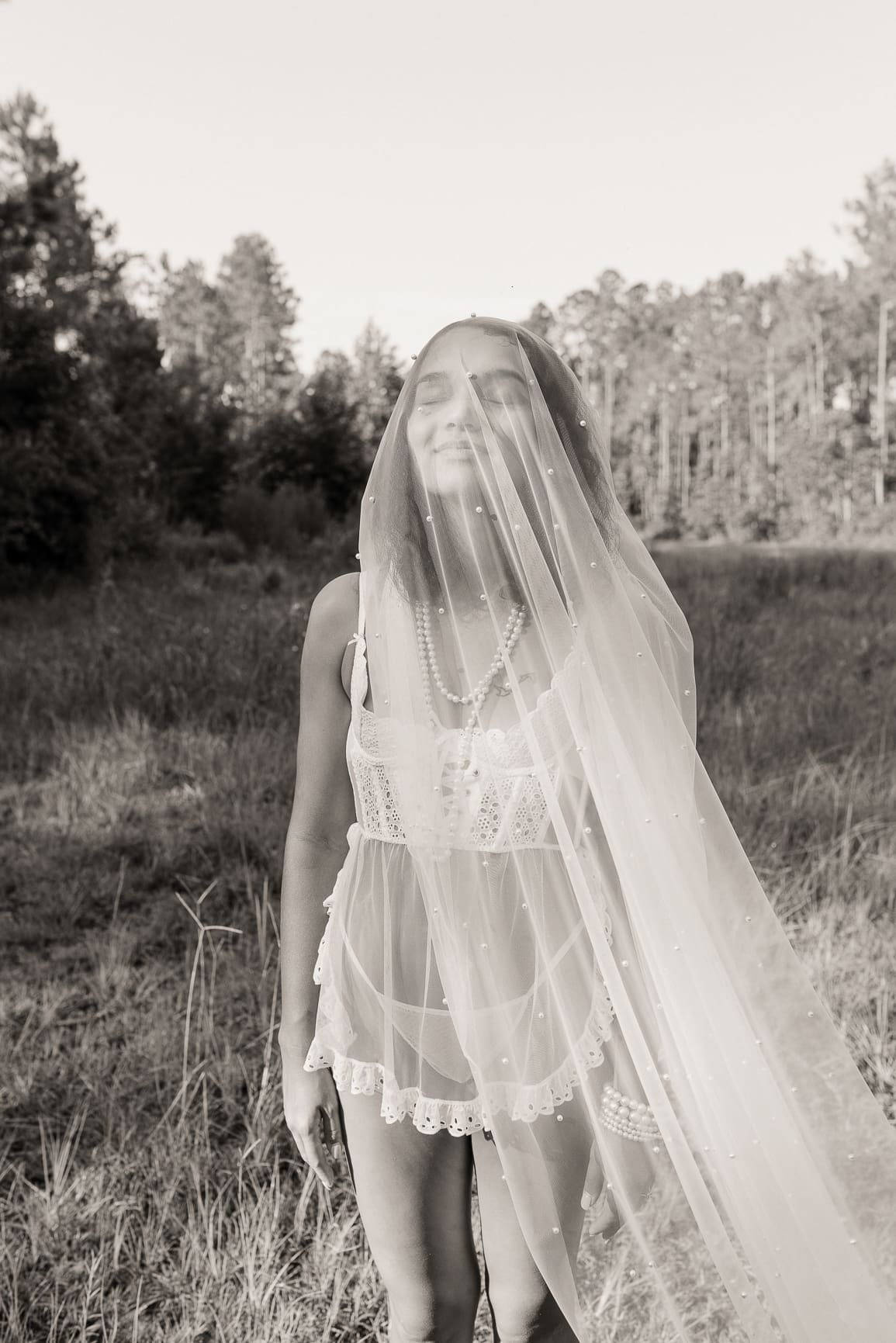Dreamlike black and white bridal portrait with flowing veil and soft light.