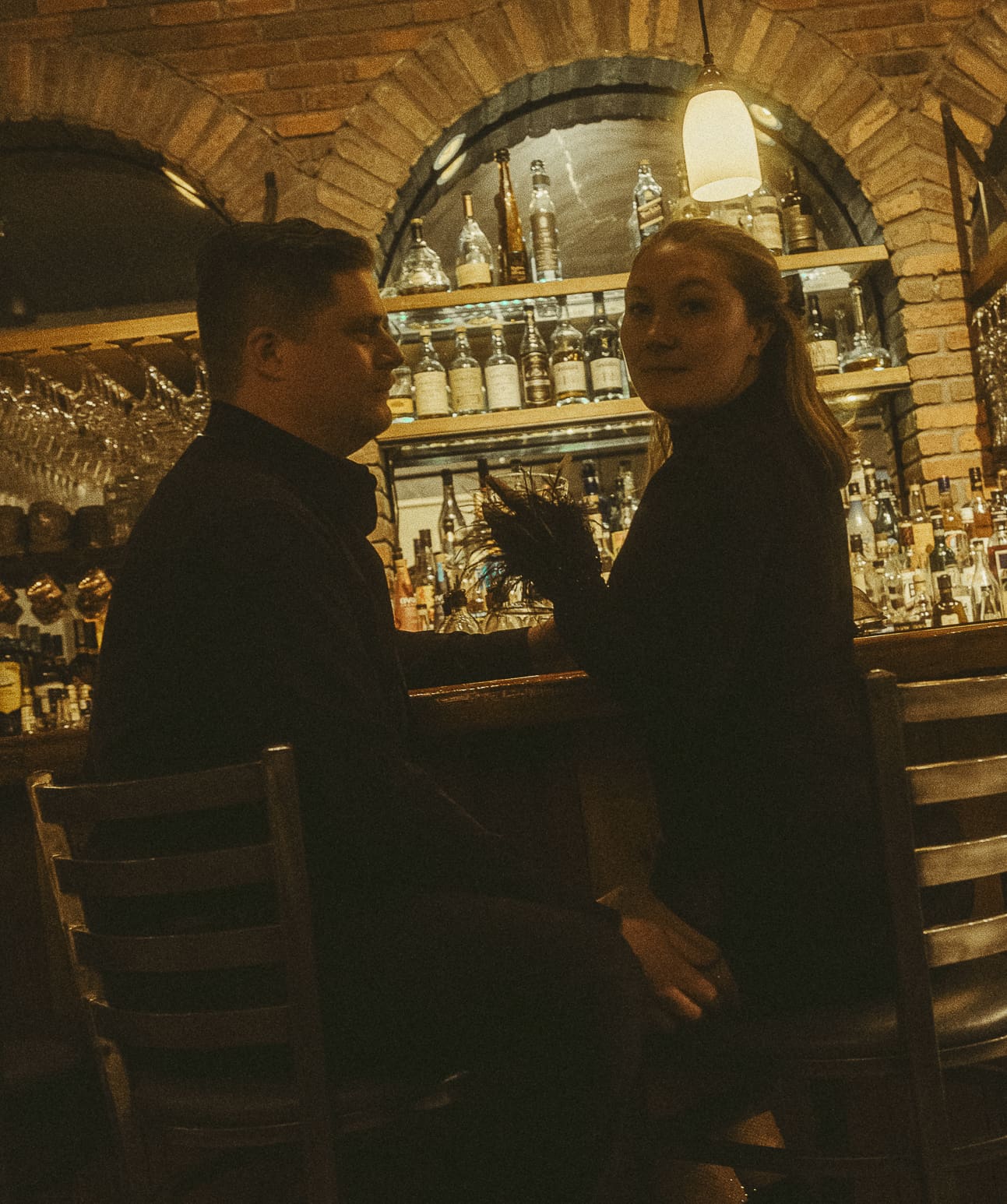 Editorial wedding portrait of a couple seated at an intimate bar, captured in warm cinematic light to reflect the art of storytelling through wedding photography.