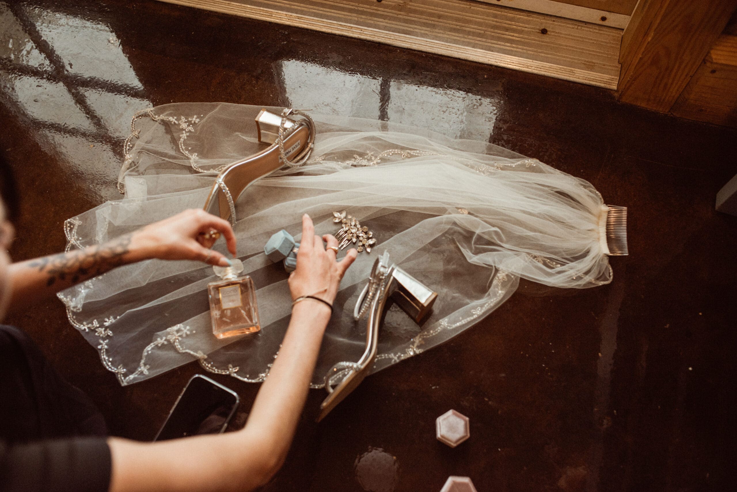 Editorial wedding detail flatly featuring perfume, jewelry, and heels styled atop a bridal veil, showcasing intentional design and visual storytelling.