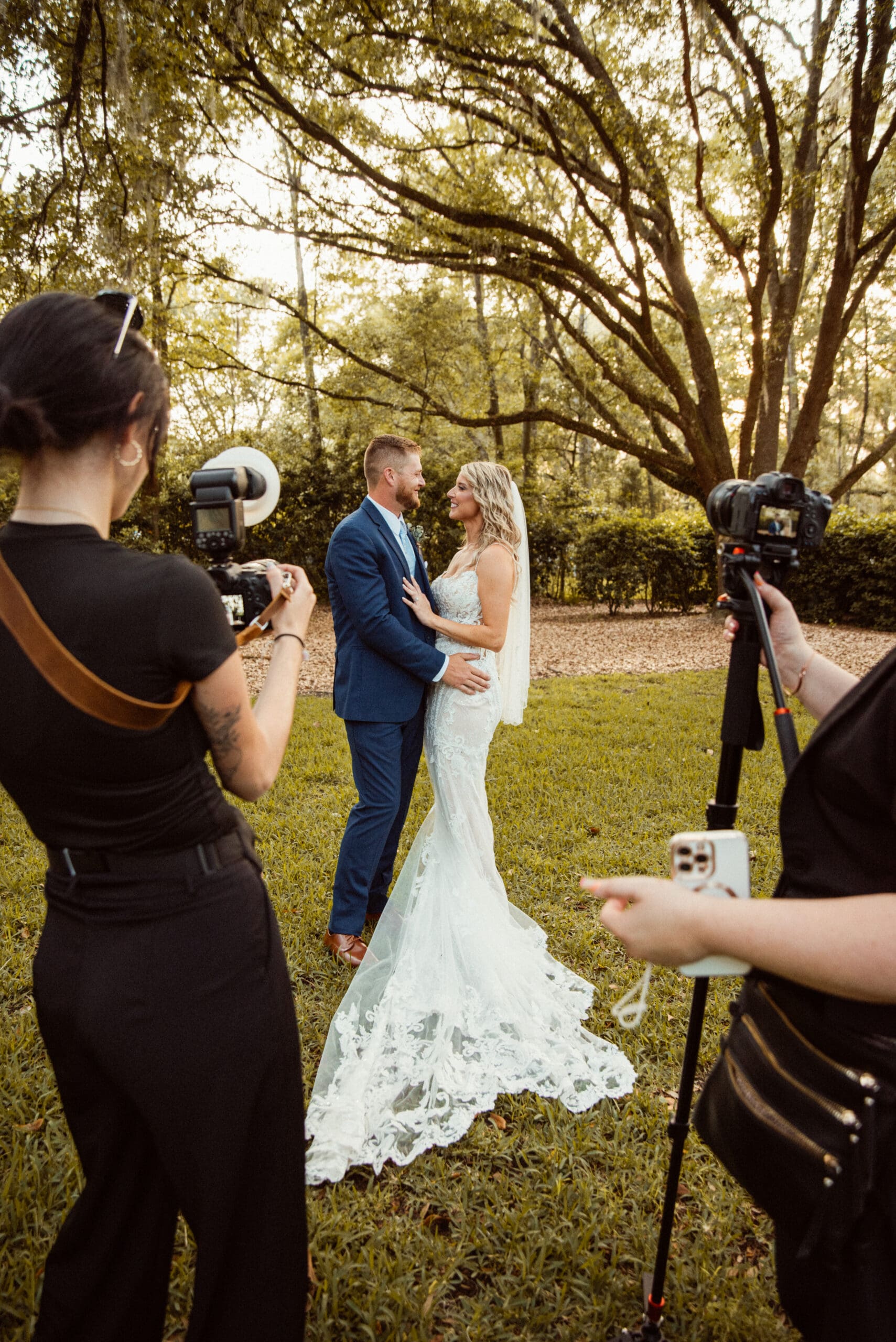 Behind-the-scenes moment of an editorial wedding photographer documenting a couple in natural light, highlighting the artistry behind each frame. 