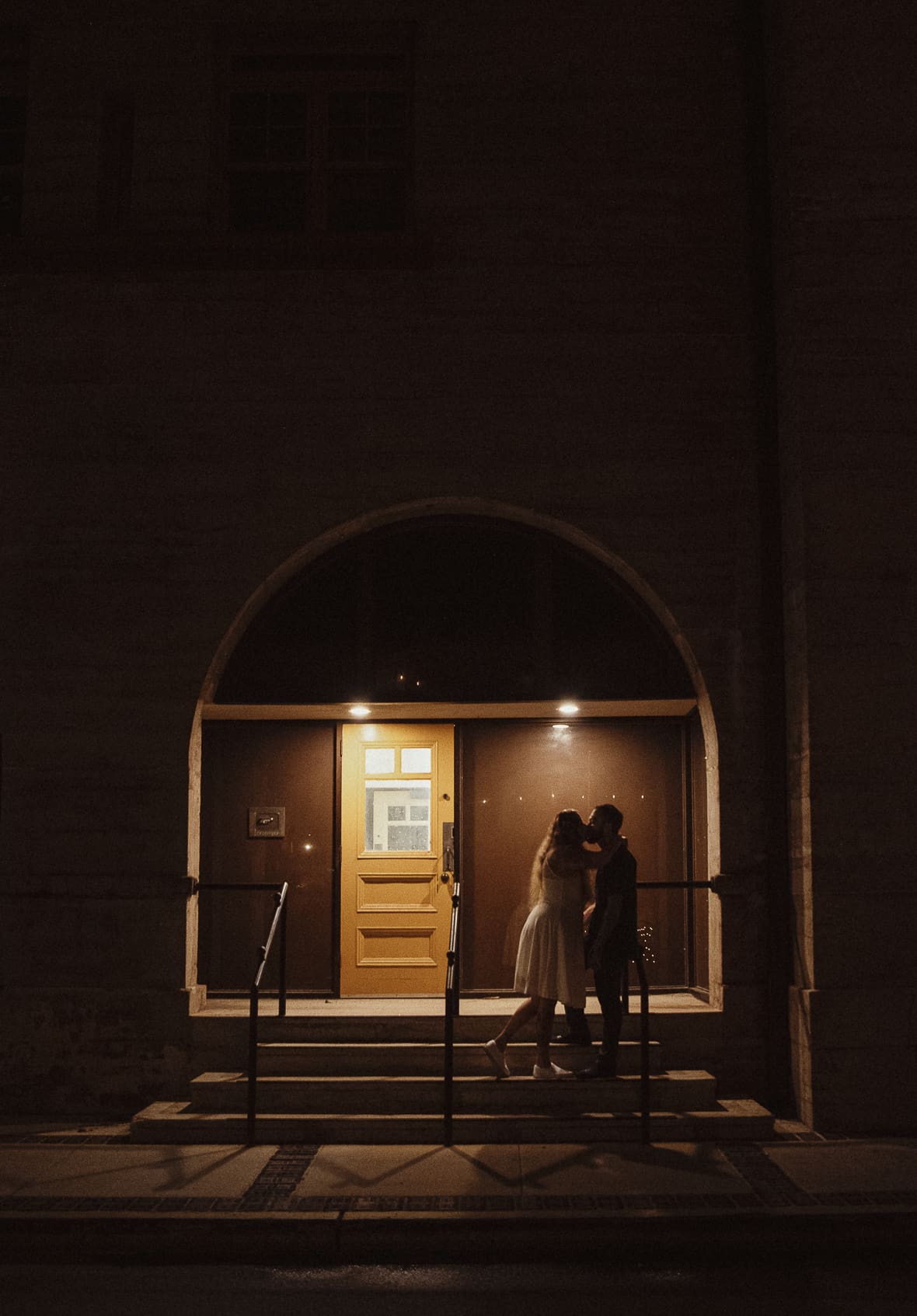 Romantic editorial wedding portrait of a couple sharing a kiss under warm light in downtown St. Augustine, photographed by Brandi Denslow.