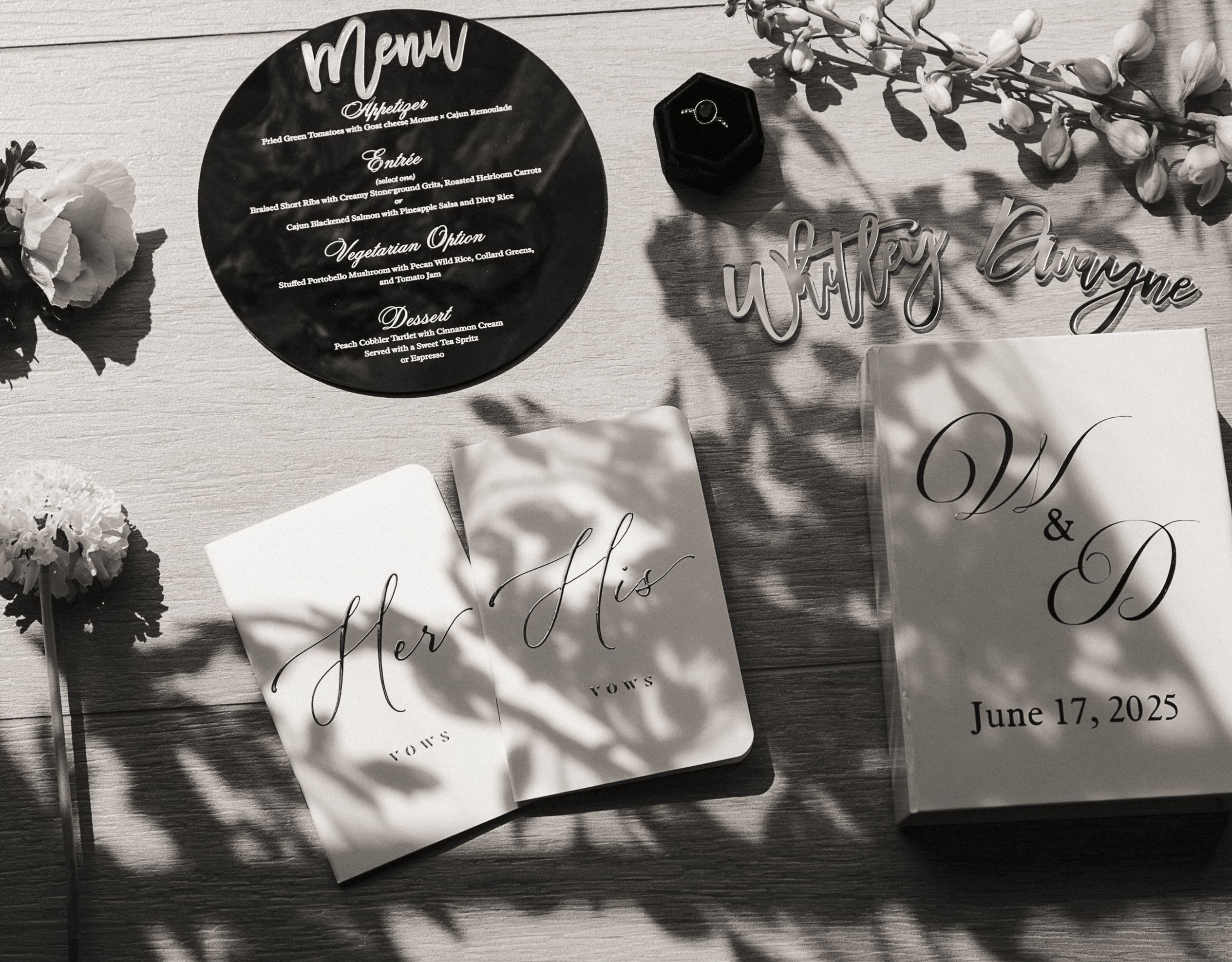  His-and-hers vow books and engagement ring styled in a black and white flat lay