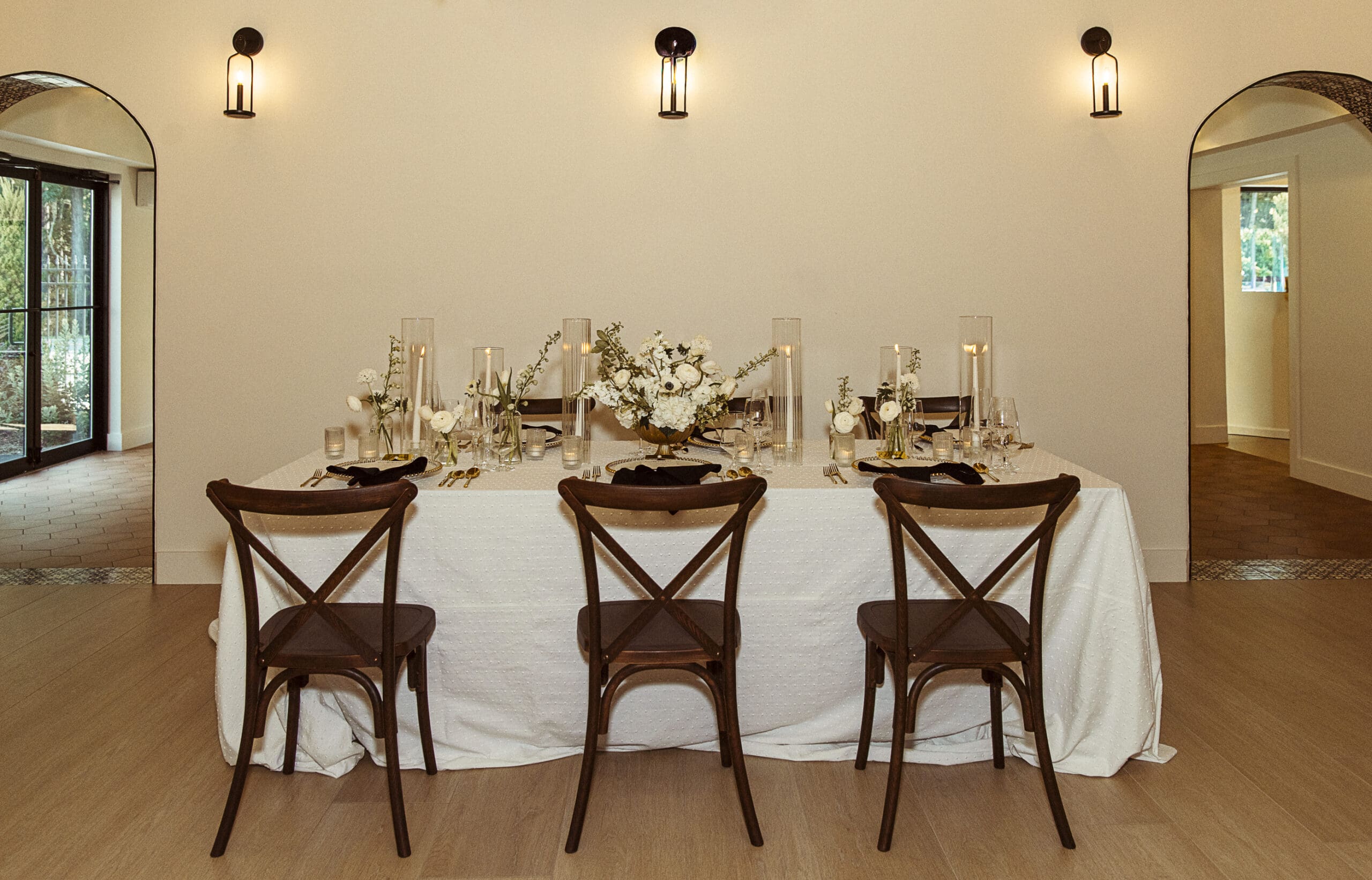 Sweetheart table set with black and white linens, gold candles, and floral centerpiece