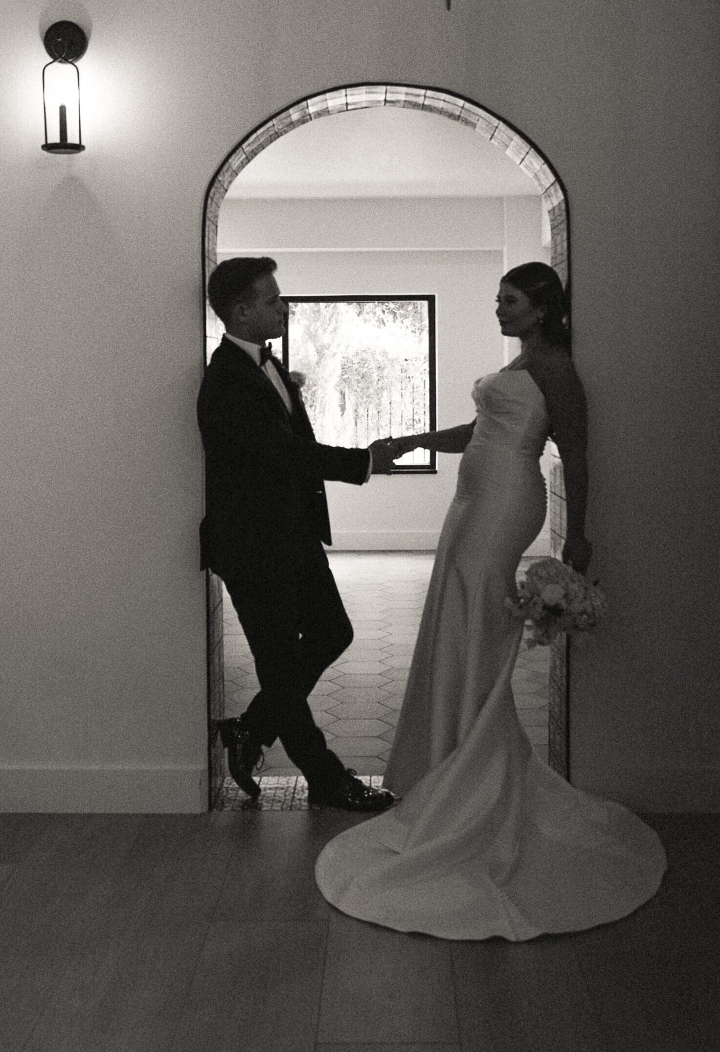 Editorial black and white portrait of a couple inside the Old Spanish Quarter, highlighting dramatic light, architectural arches, and cinematic elegance.