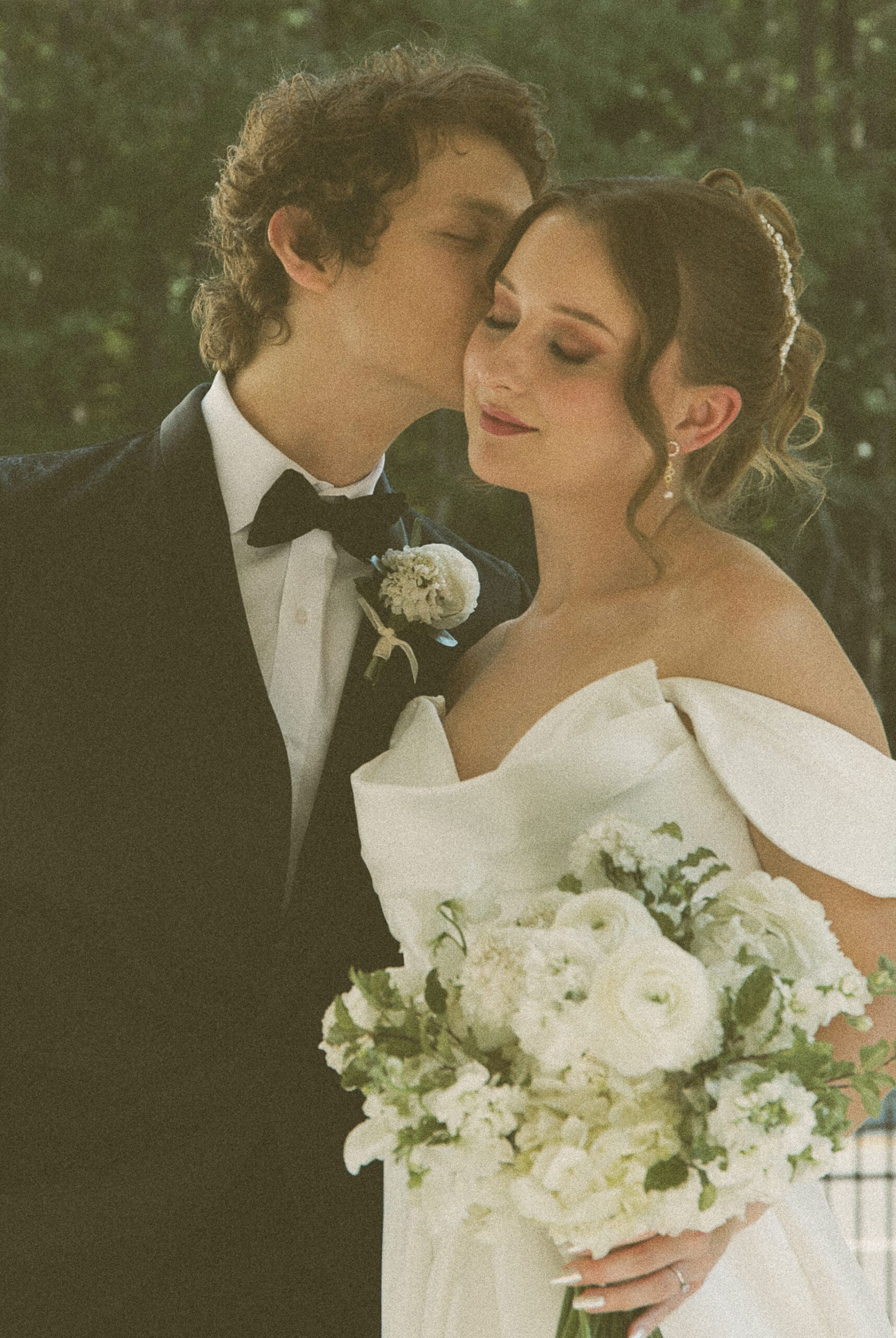 Close-up of the groom kissing the bride's forehead, editorial wedding portrait