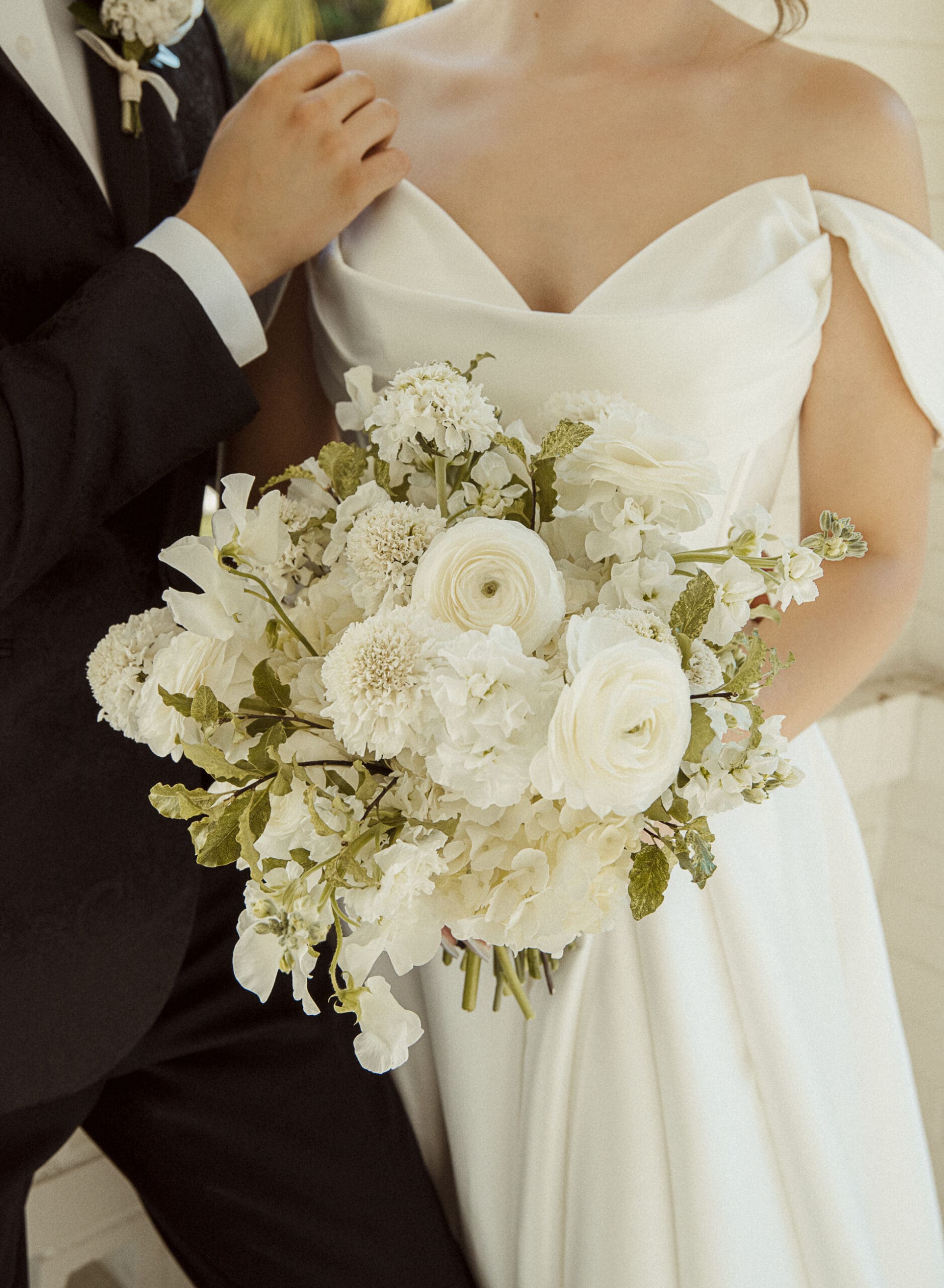 Close-up detail of the bride's white floral bouquet against her gown