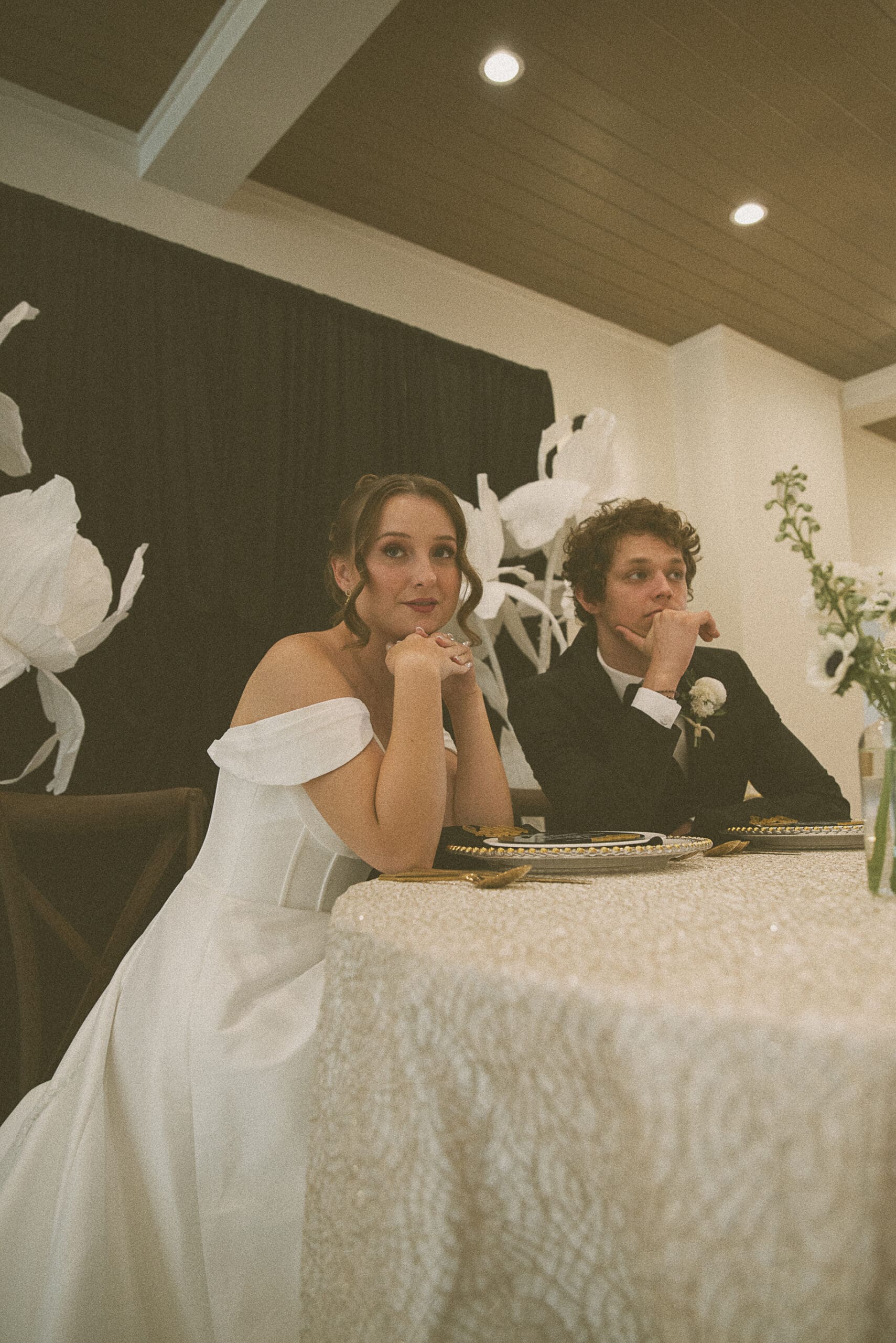 Bride and groom seated together at the reception table, candid black-and-white moment