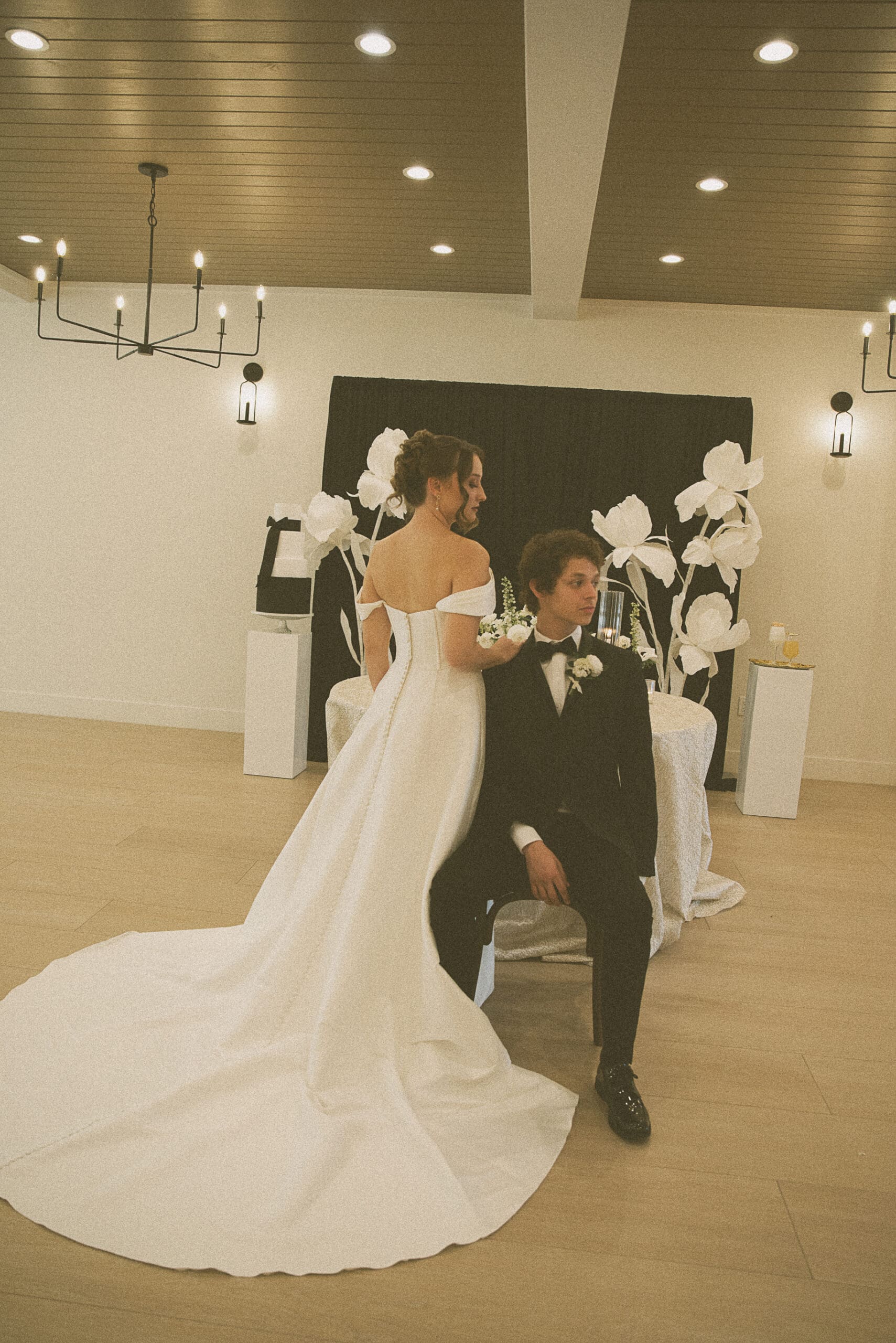 Bride and groom portrait against an oversized paper flower reception backdrop