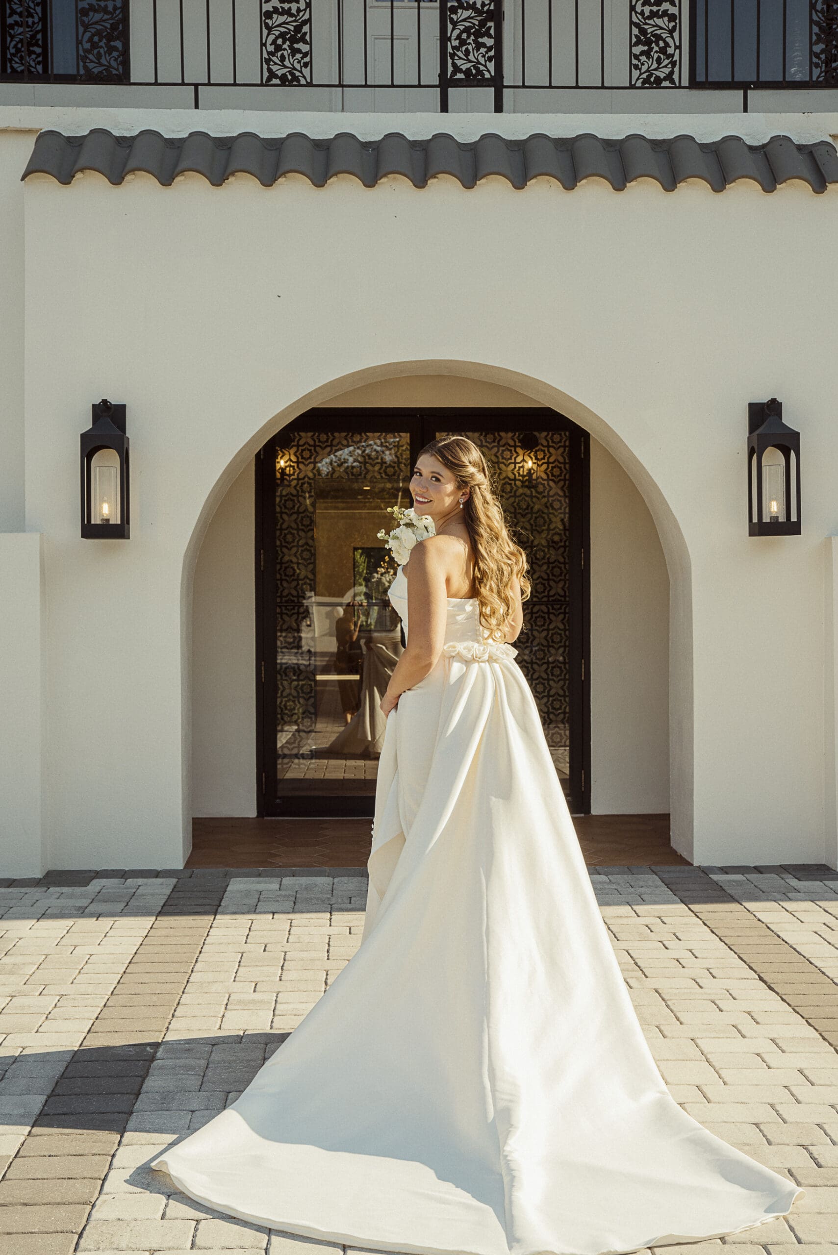 Bride glancing over her shoulder in a Spanish Revival archway during a Jacksonville editorial wedding shoot