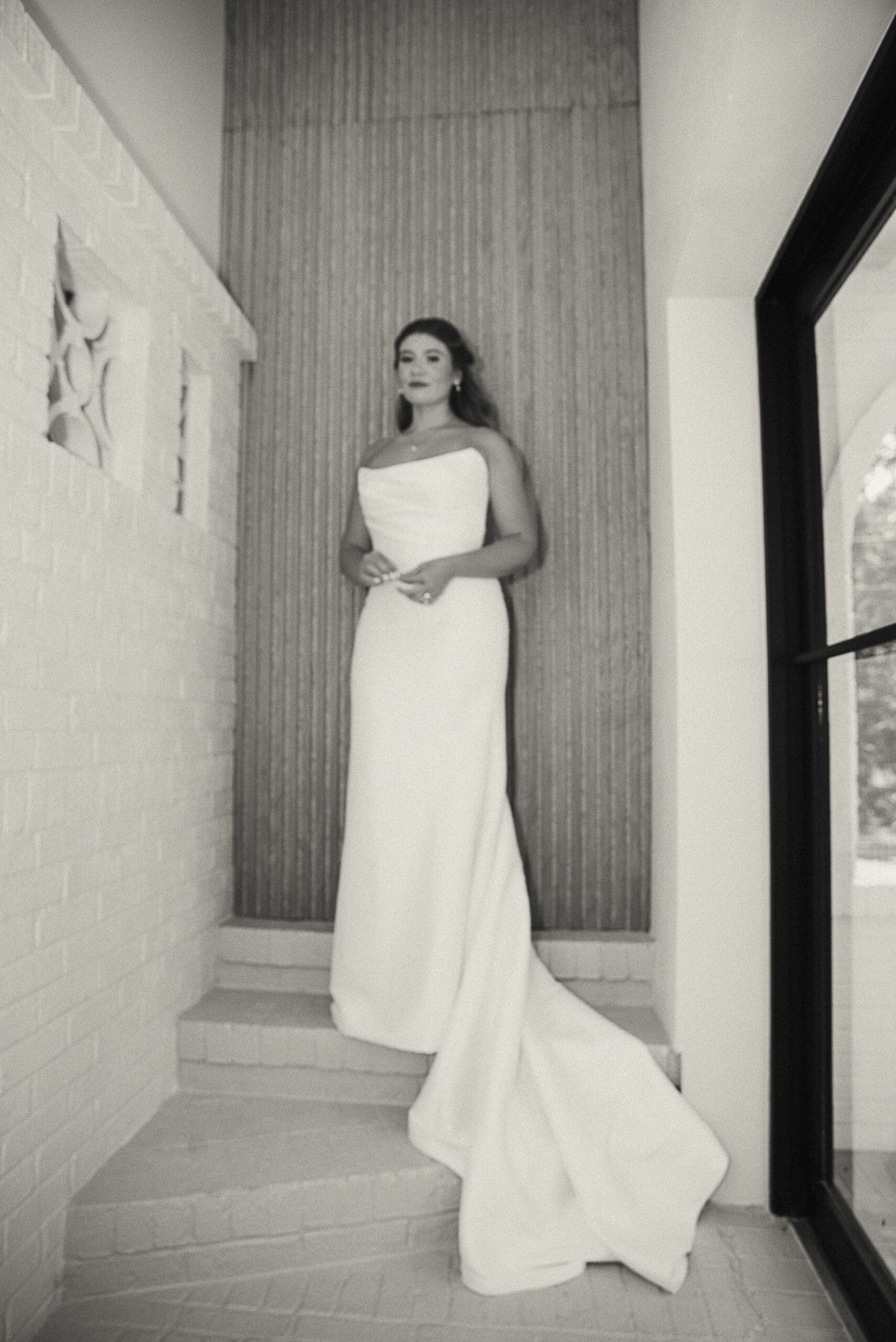 Black-and-white bridal portrait on the interior staircase, wearing a strapless gown