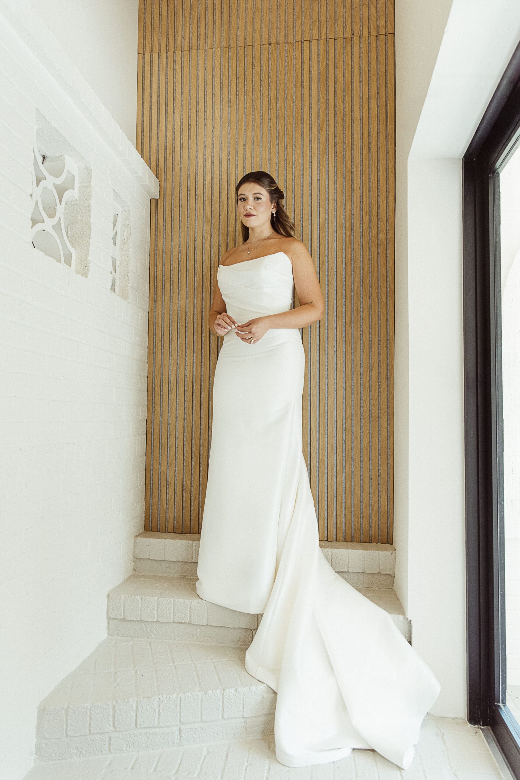 Bride in sleek white gown standing against a warm textured wall at the Old Spanish Quarter, blending minimalist design with classic romance.