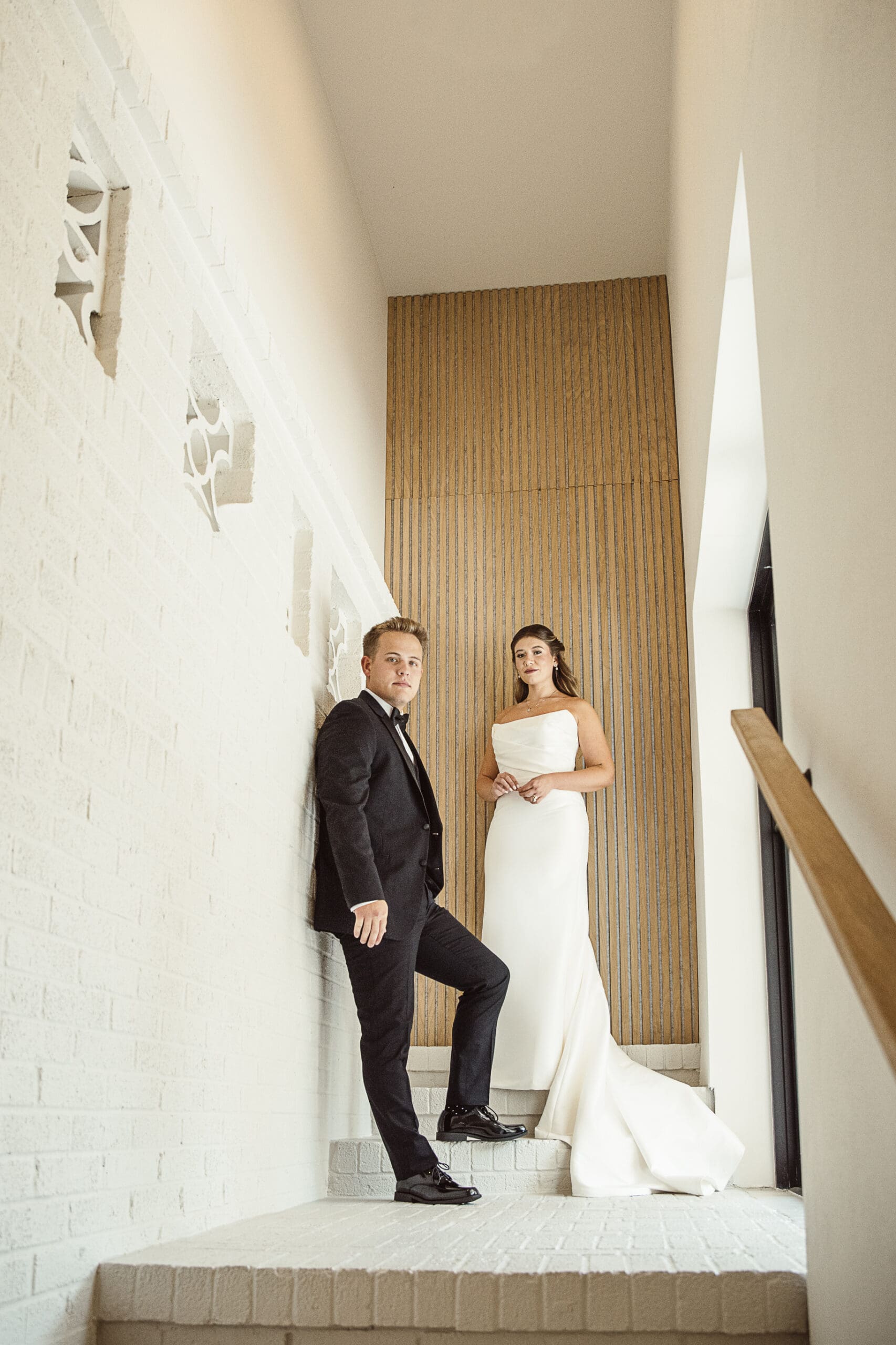 Bride and groom portrait against a wood-paneled stairwell at the venue