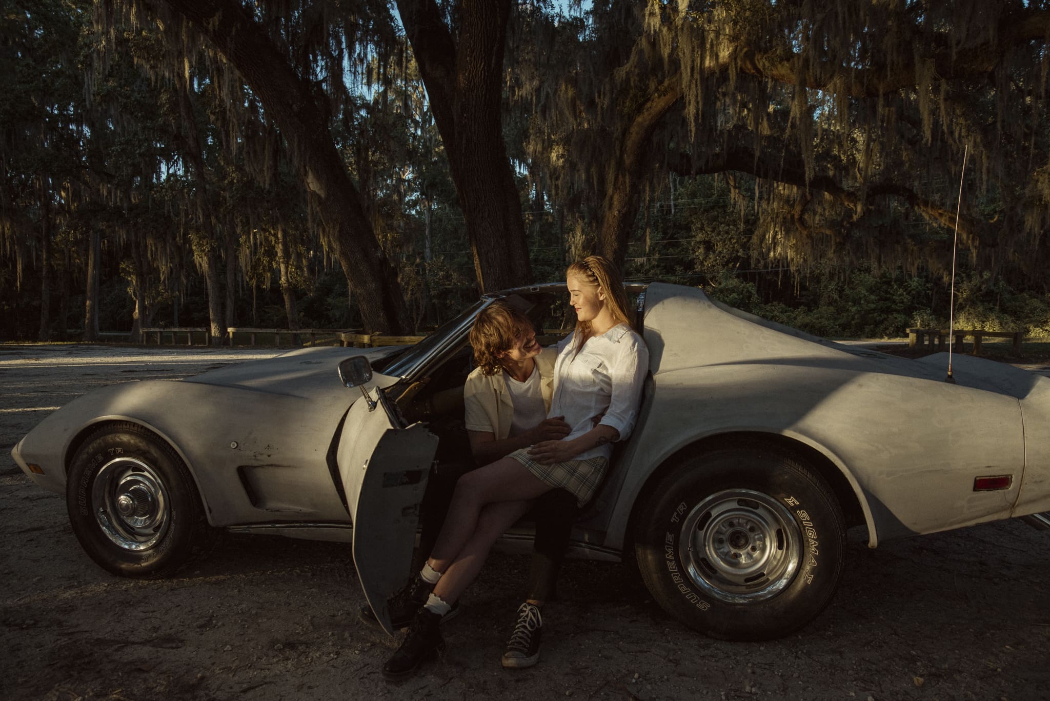 Couple sitting in a vintage Corvette during an editorial couples session along the St. Johns River, photographed at golden hour with moody light and cinematic motion.