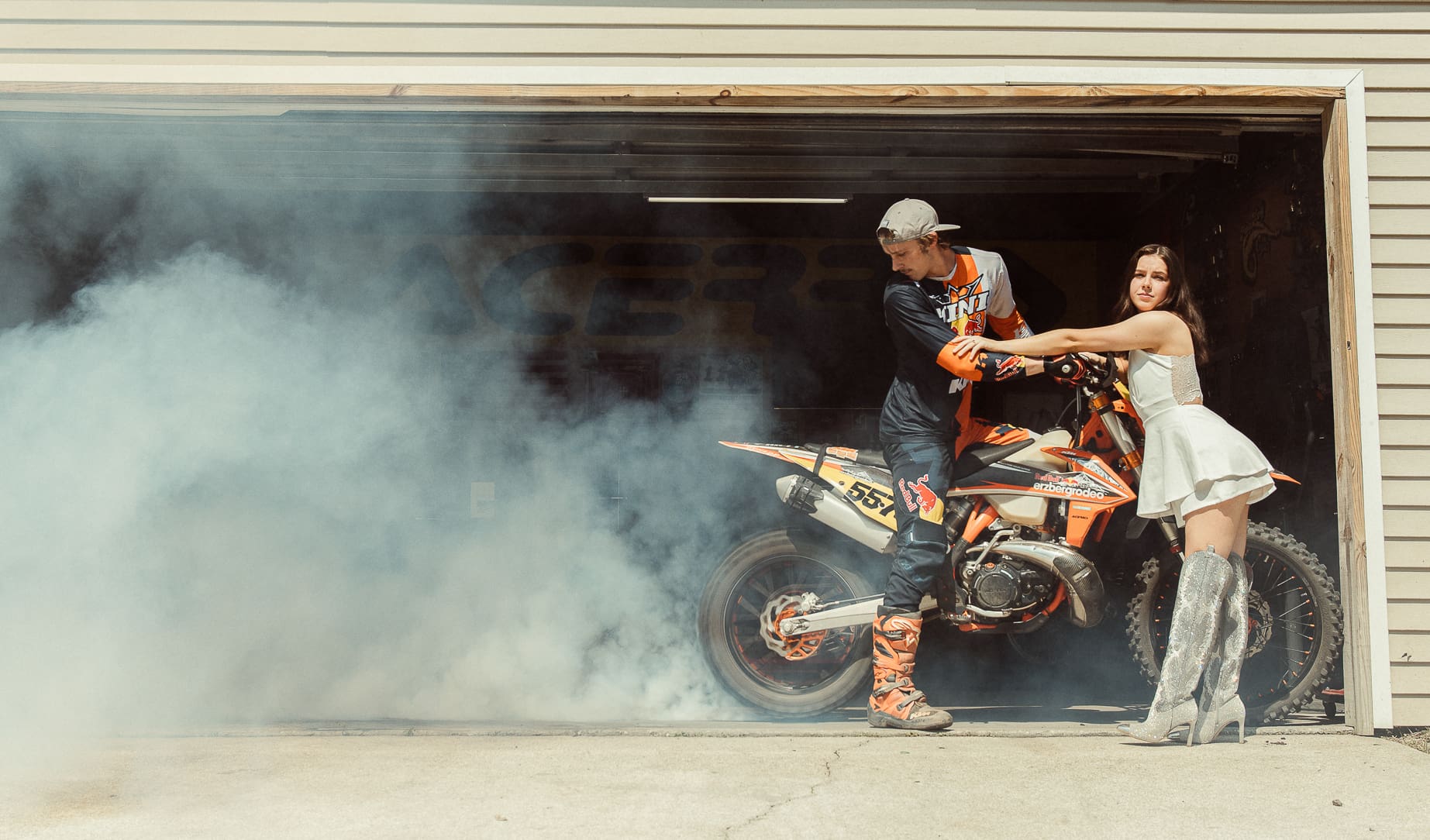 Bold editorial engagement photo featuring a couple with a dirt bike and smoke, showcasing how creatively directed engagement sessions reflect personality, edge, and personal interests. 