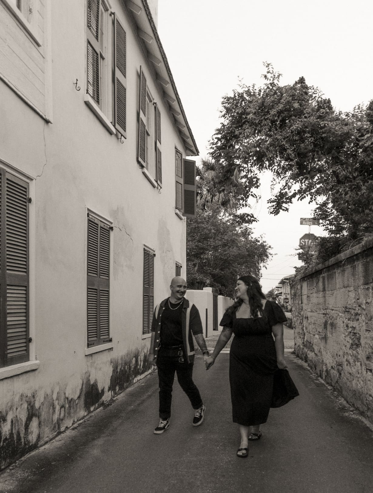 Black and white engagement photos in St. Augustine capturing a couple walking hand in hand during a relaxed date night session. 