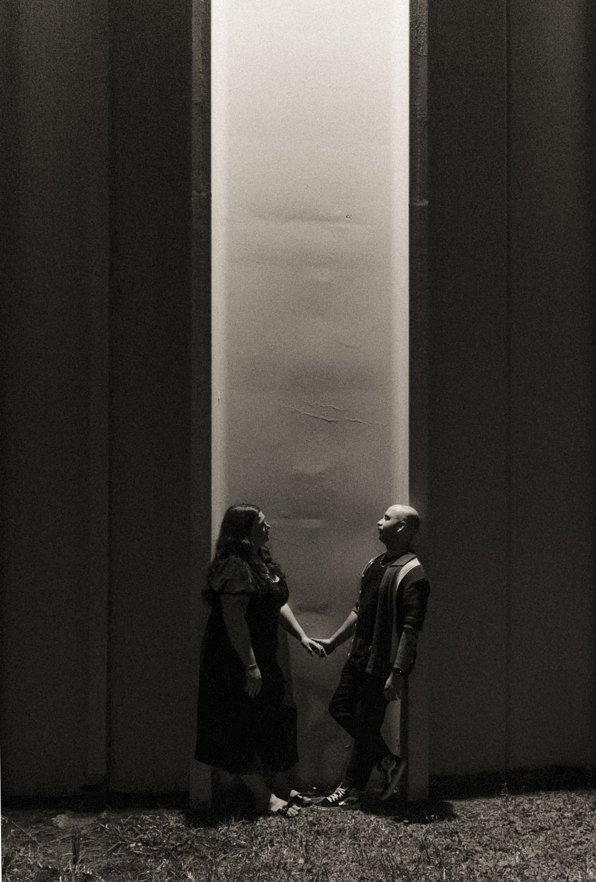 Moody black and white engagement photo of a couple holding hands at night, photographed with intentional lighting as part of a creatively directed editorial engagement session. 