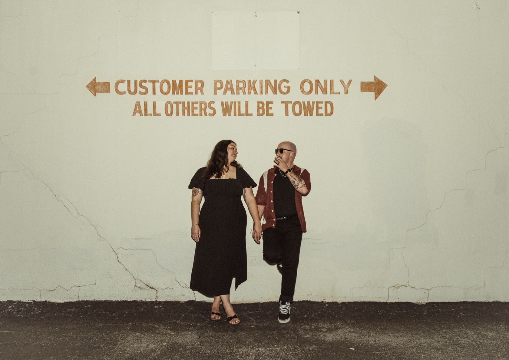 Rebecca and Noah standing beneath a parking sign during a downtown St. Augustine engagement session, captured with bold editorial posing and urban night photography style. 