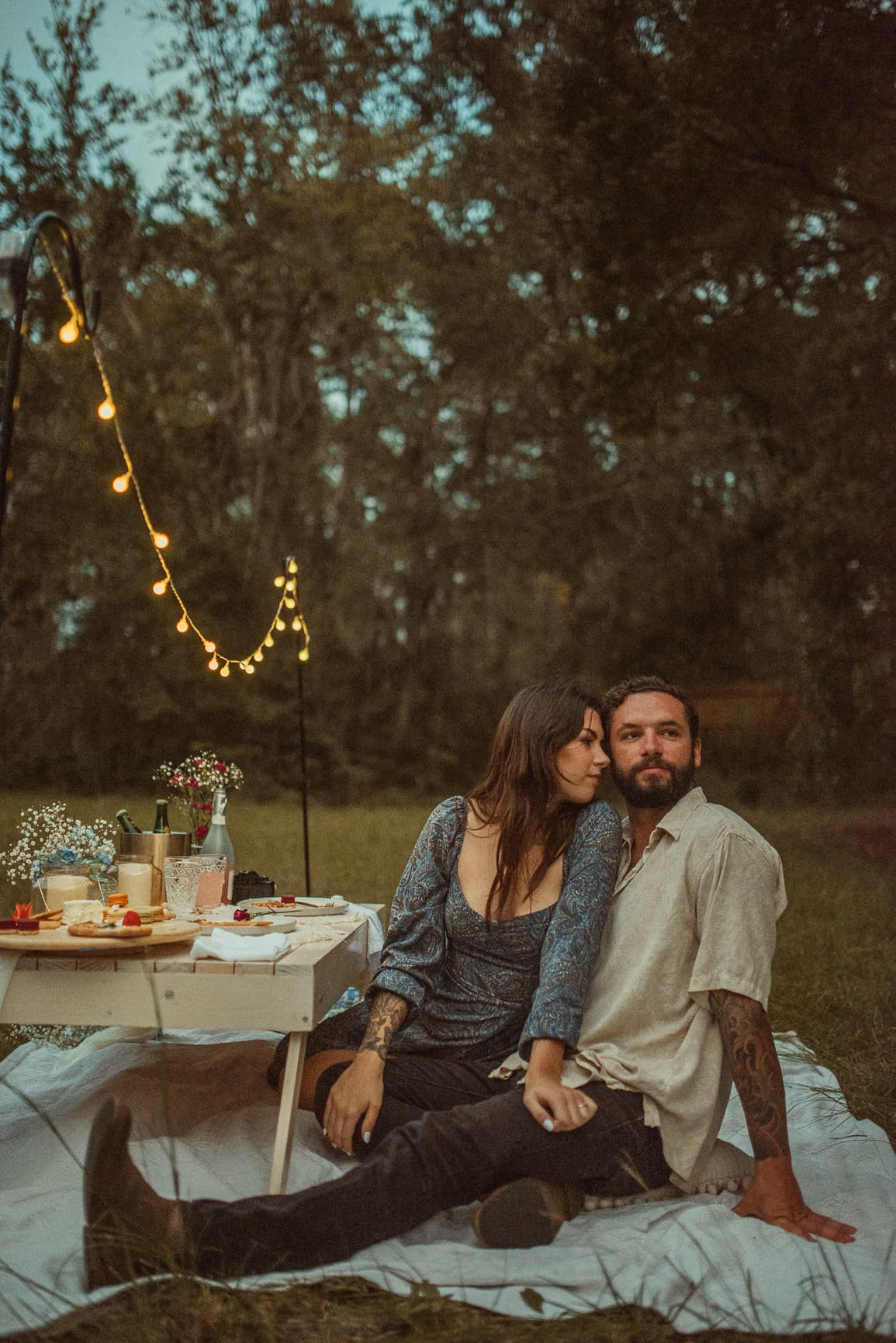 Couple wearing soft, romantic engagement photo outfits with flowy fabric and neutral tones during a sunset session