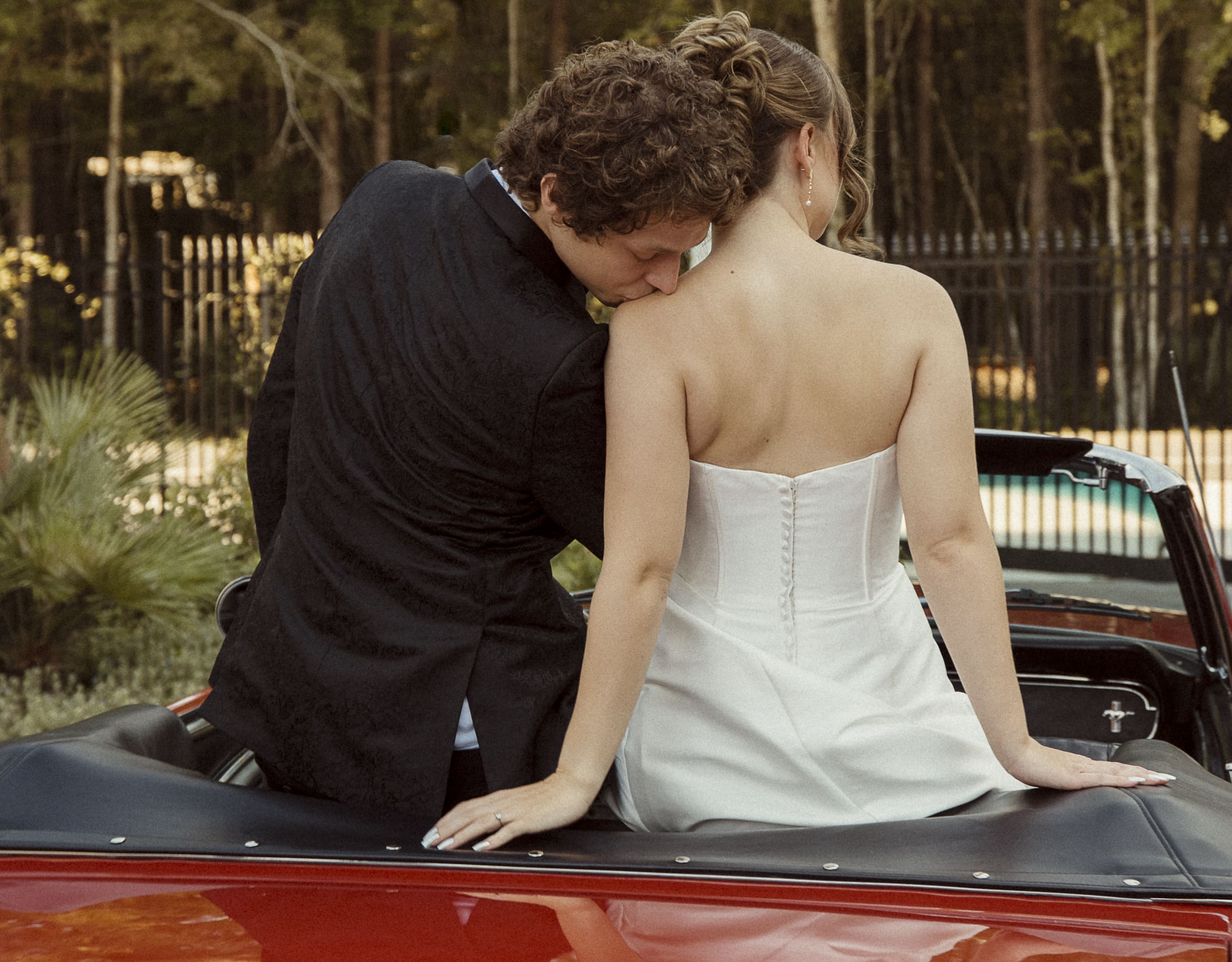 Bride and groom sitting together on a vintage car, sharing a quiet affectionate moment and feeling supported on their wedding day