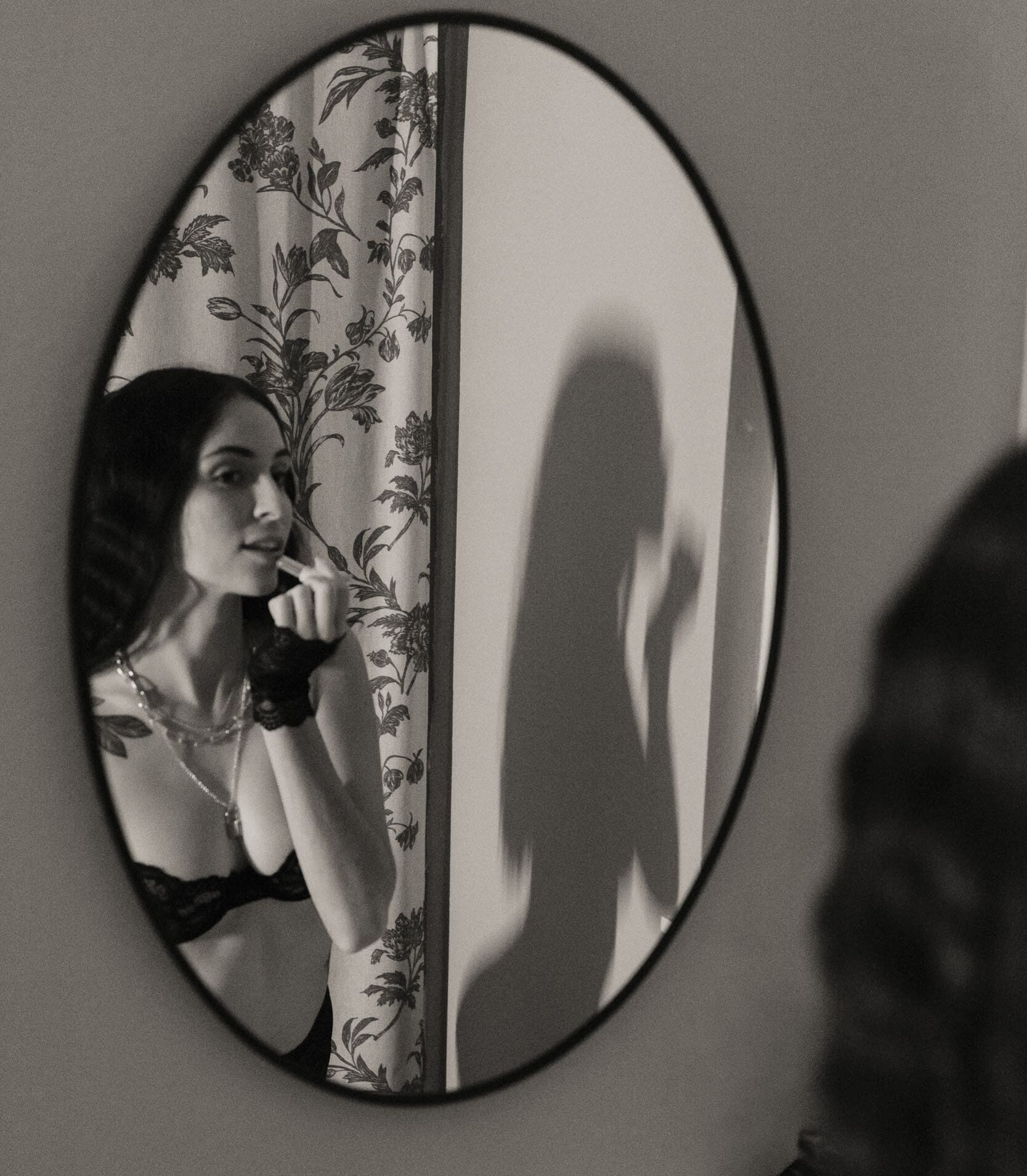Woman reflected in a mirror during an embodiment photography session, gently observing herself with presence and self-awareness