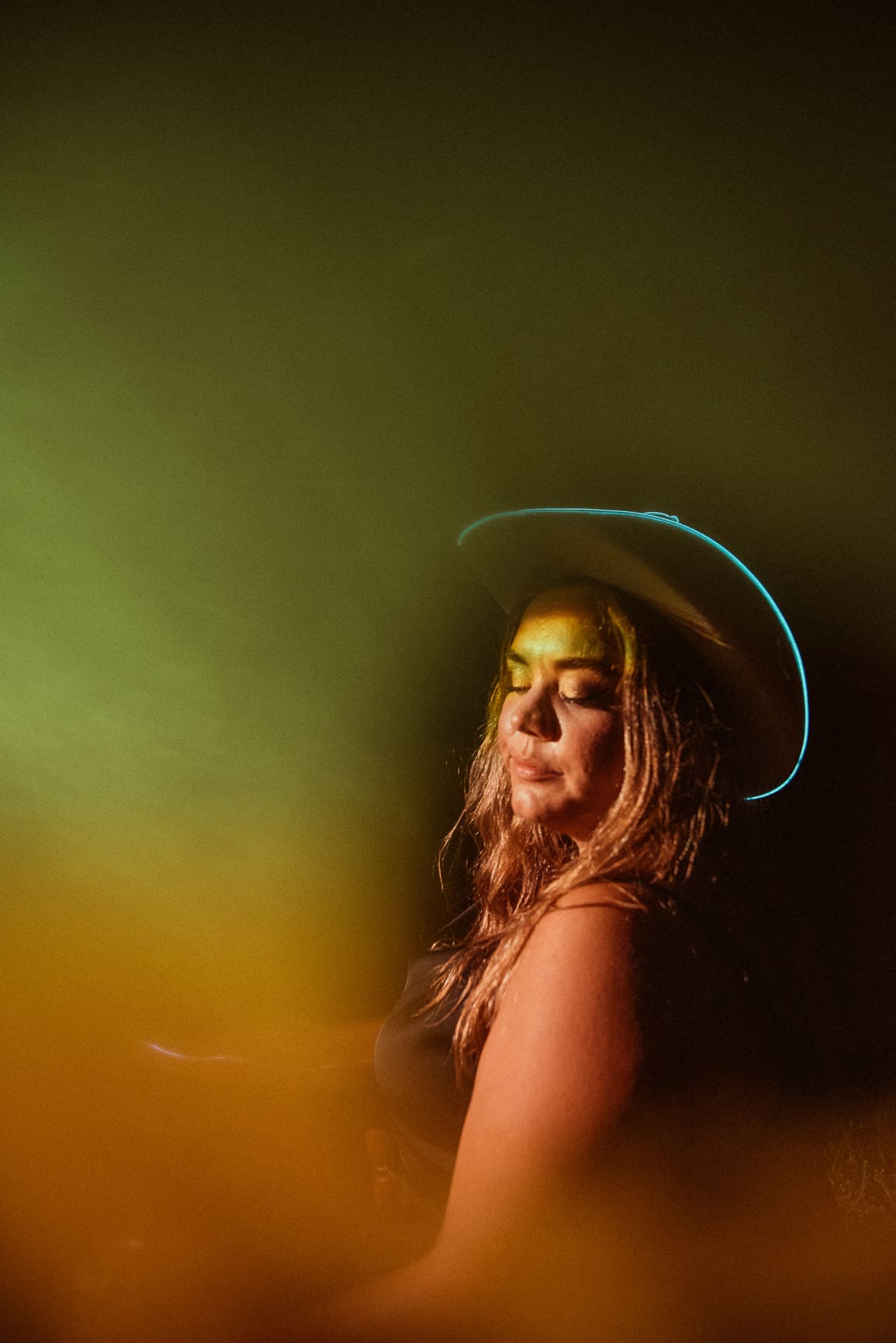 Creative embodiment portrait of a woman wearing a hat, photographed with flash lighting to express confidence, energy, and self-expression