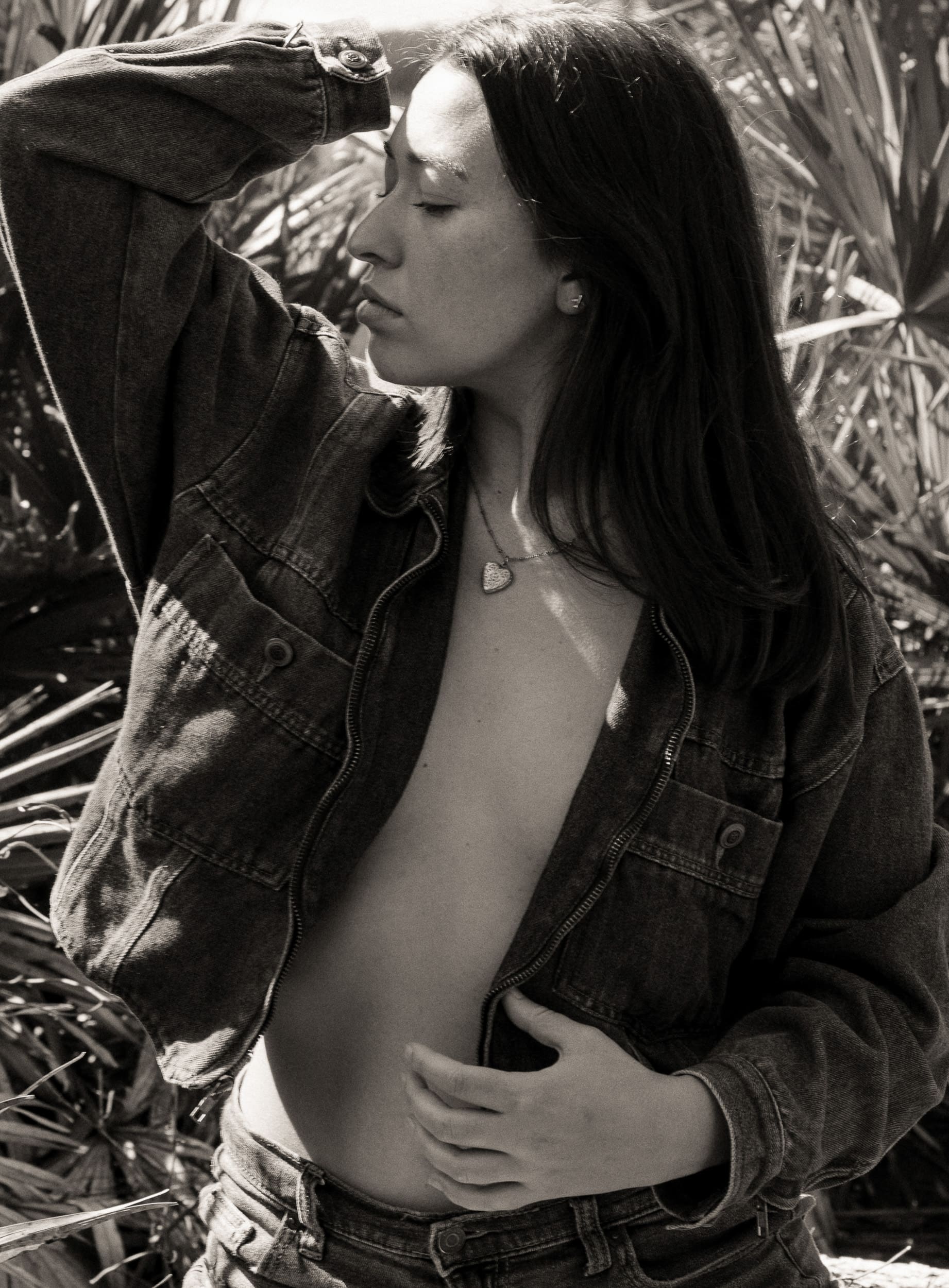 Black and white embodiment portrait of a woman wearing an open denim jacket, expressing grounded confidence, vulnerability, and self-connection