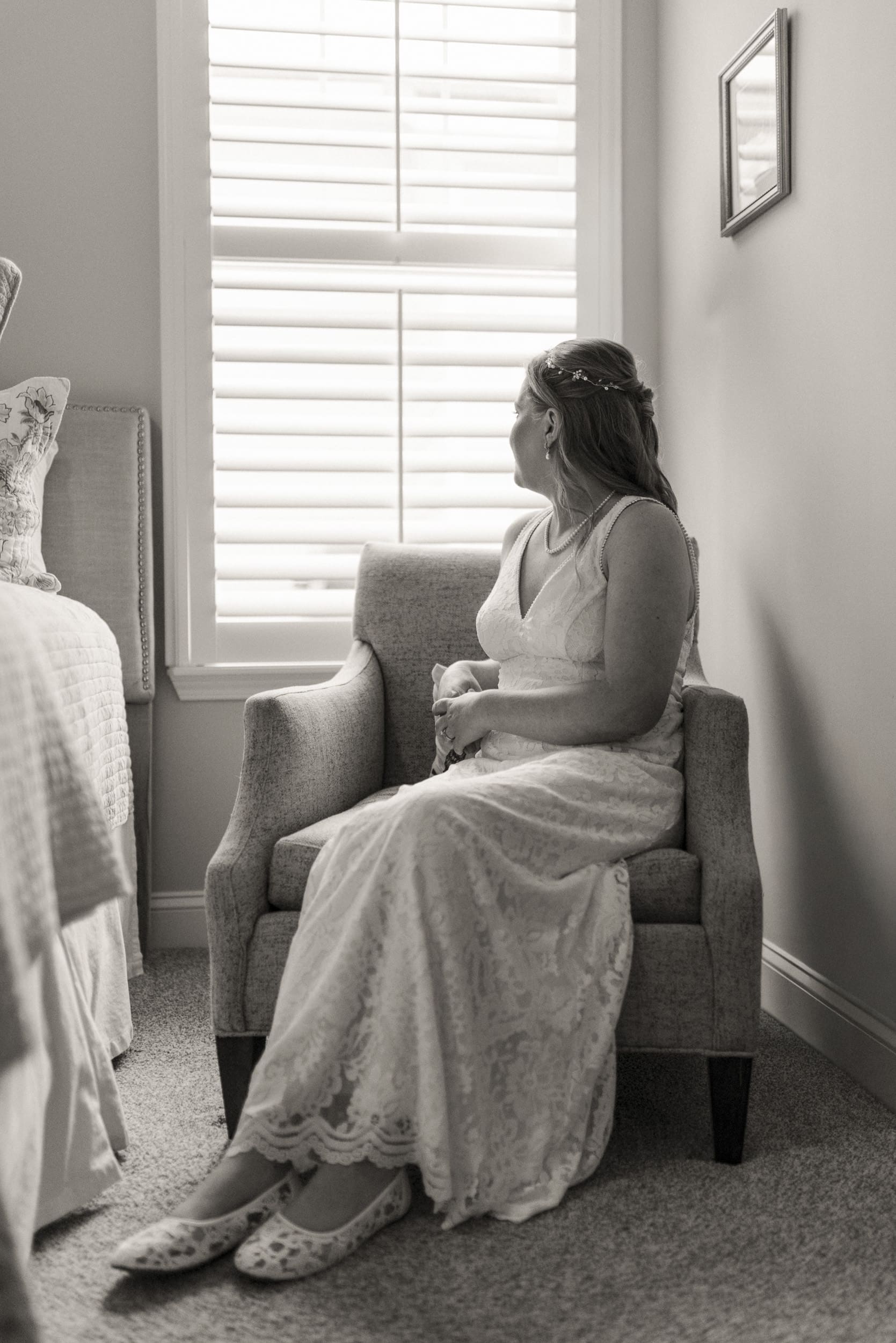 Bride sitting quietly in a chair near a window, taking a calm and reflective moment during wedding morning preparations