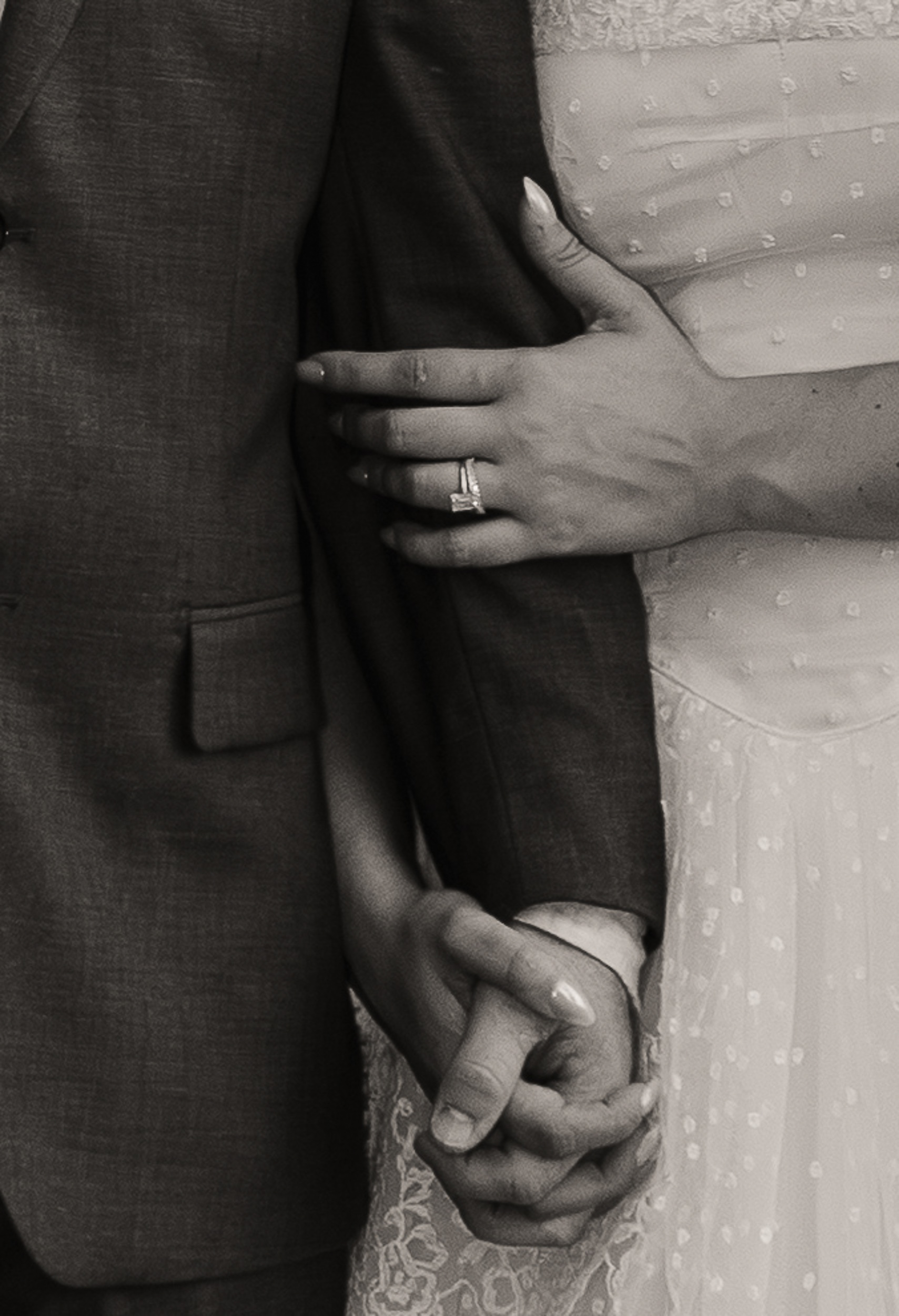 Close-up of the bride's hand with an emerald-cut ring resting on the groom's arm as they hold hands