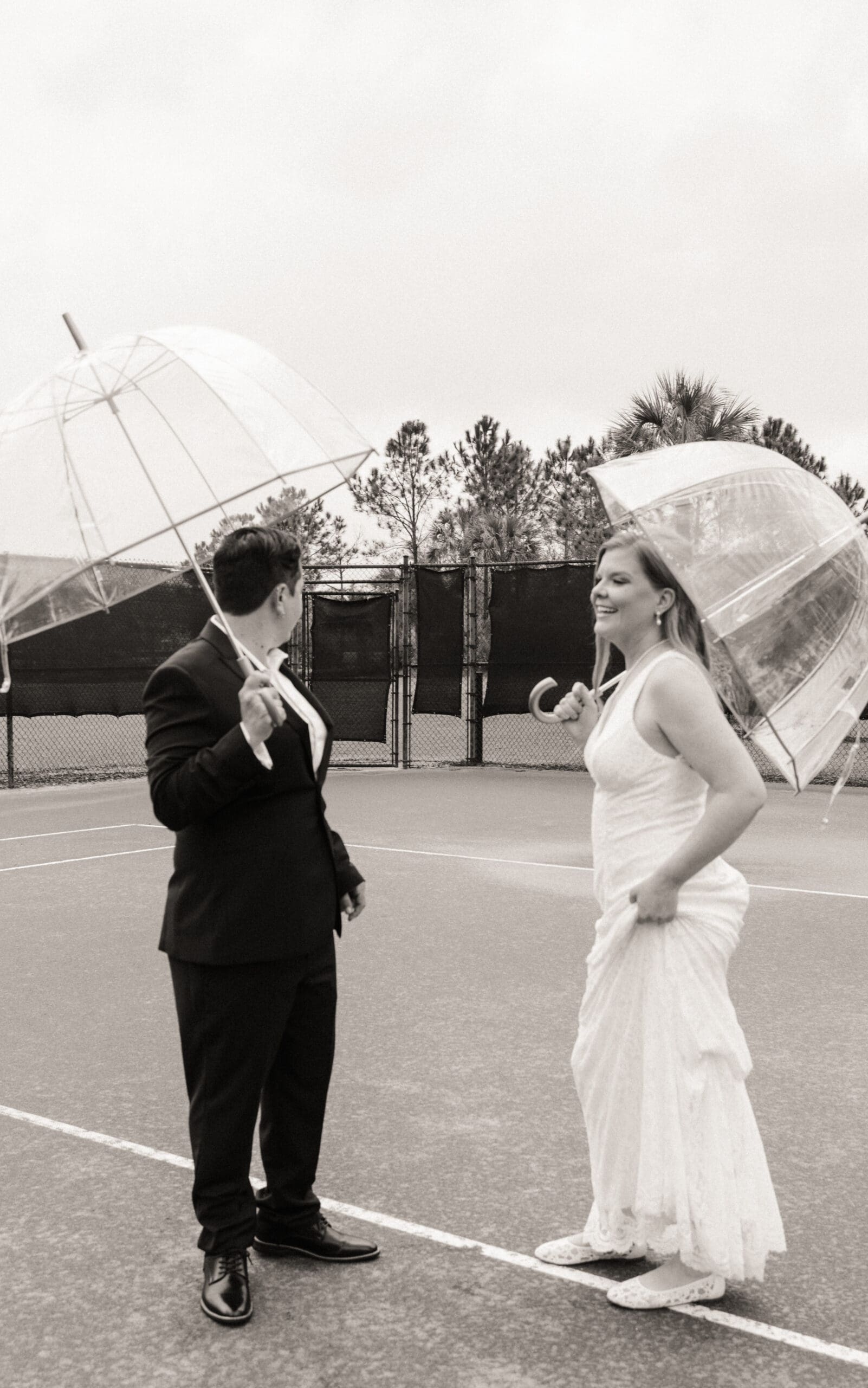 Playful St. Augustine wedding portrait of a couple walking in the rain with umbrellas. 