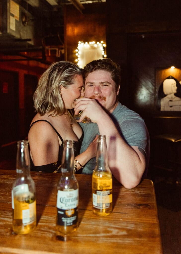 Couple sharing drinks at a bar in downtown St. Augustine during a romantic engagement session photographed by a St. Augustine wedding photographer. 