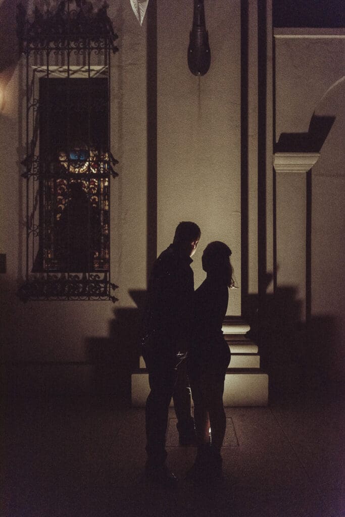 Bride and groom silhouetted against glowing light in a historic St. Augustine courtyard at night. 