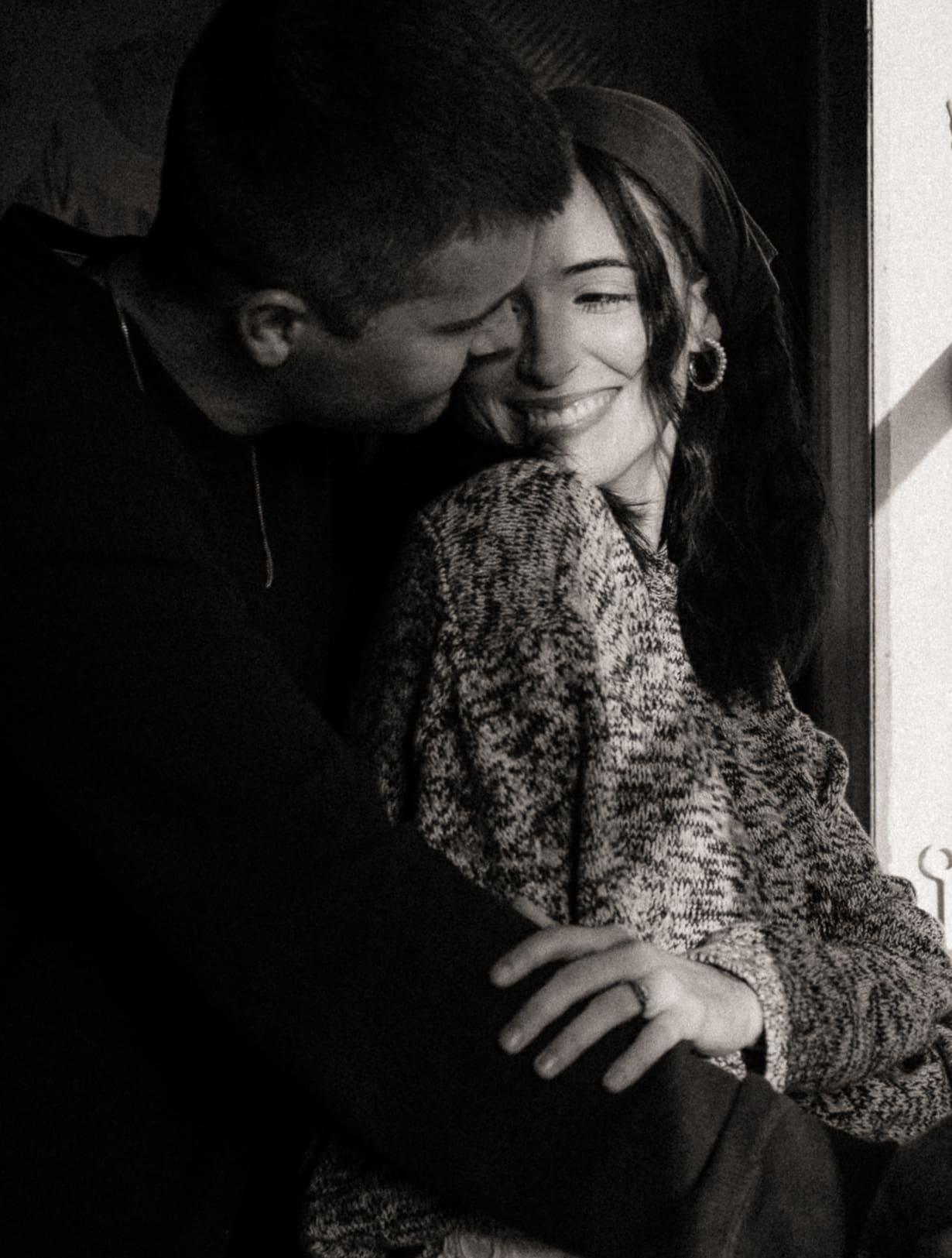 Black and white candid photograph of a couple sharing a quiet, intimate moment, focused on emotional connection rather than posing