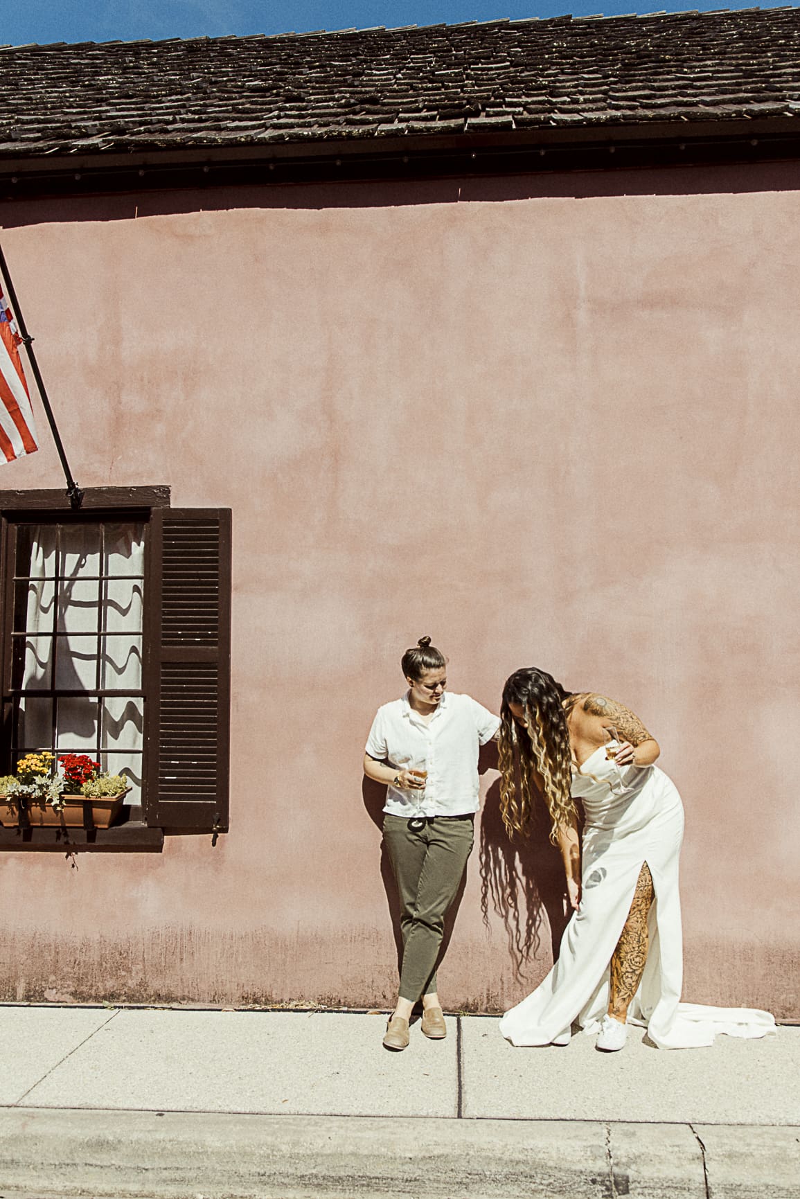 Wedding couple laughing together against colorful historic wall in downtown St. Augustine, Florida. 
