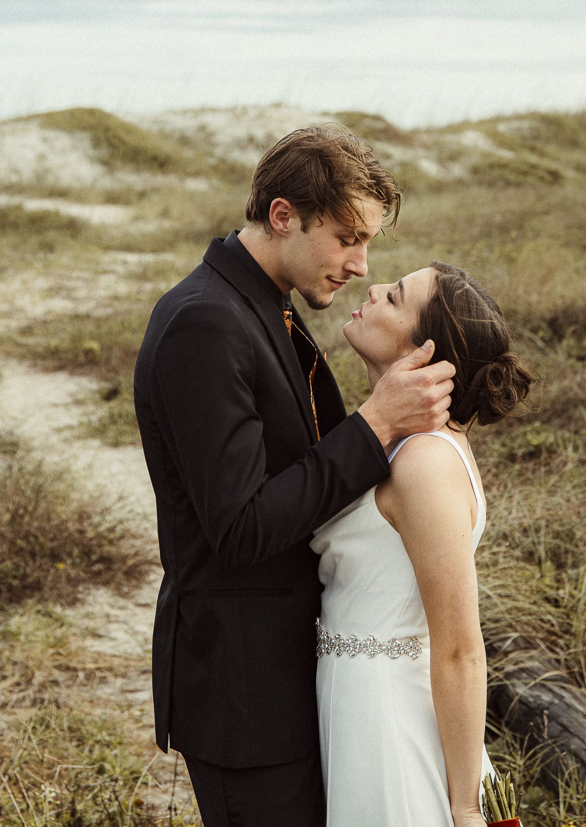Emotional wedding portrait of a couple holding each other closely in a natural outdoor setting,  photographed with softness and intention.