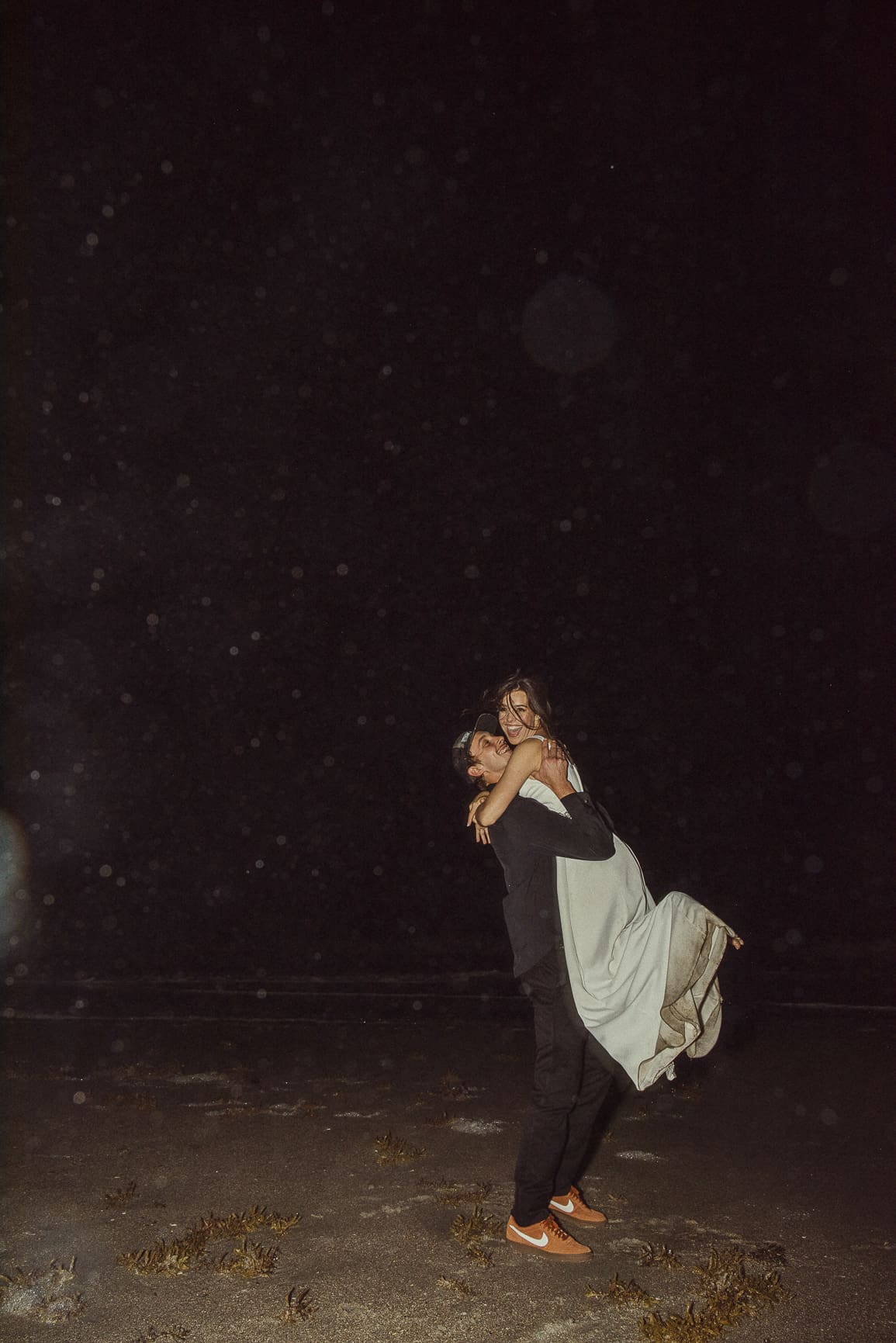 Bride and groom celebrating at night during a dramatic St Augustine wedding portrait session photographed with flash at the beach.