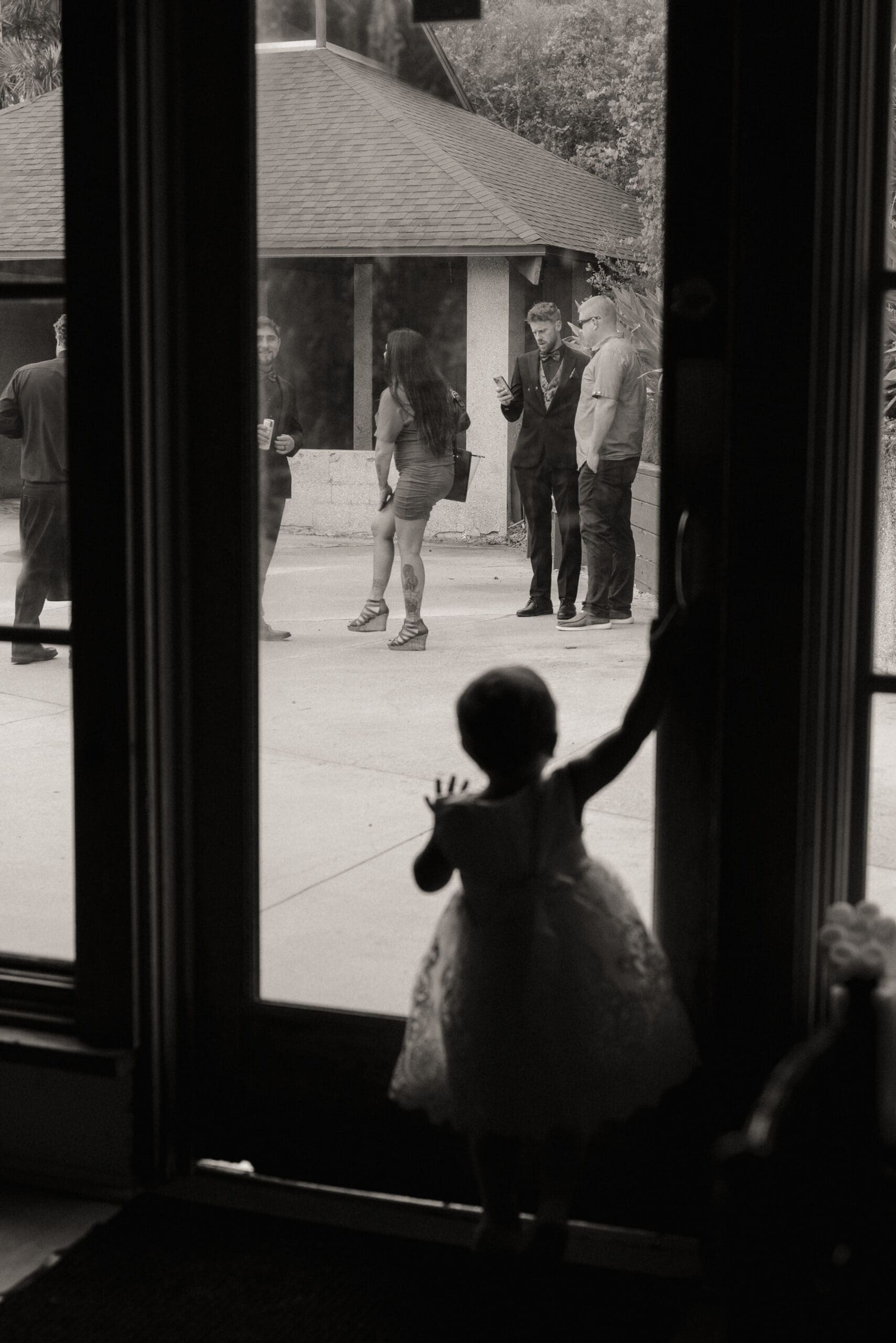 A quiet candid moment of a child silhouetted in a doorway during a wedding day, captured without interruption