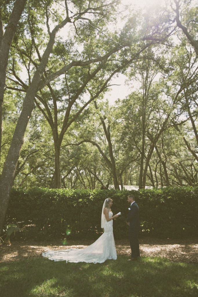 Bride and groom exchanging vows beneath tall oak trees during an intimate St. Augustine wedding ceremony. 