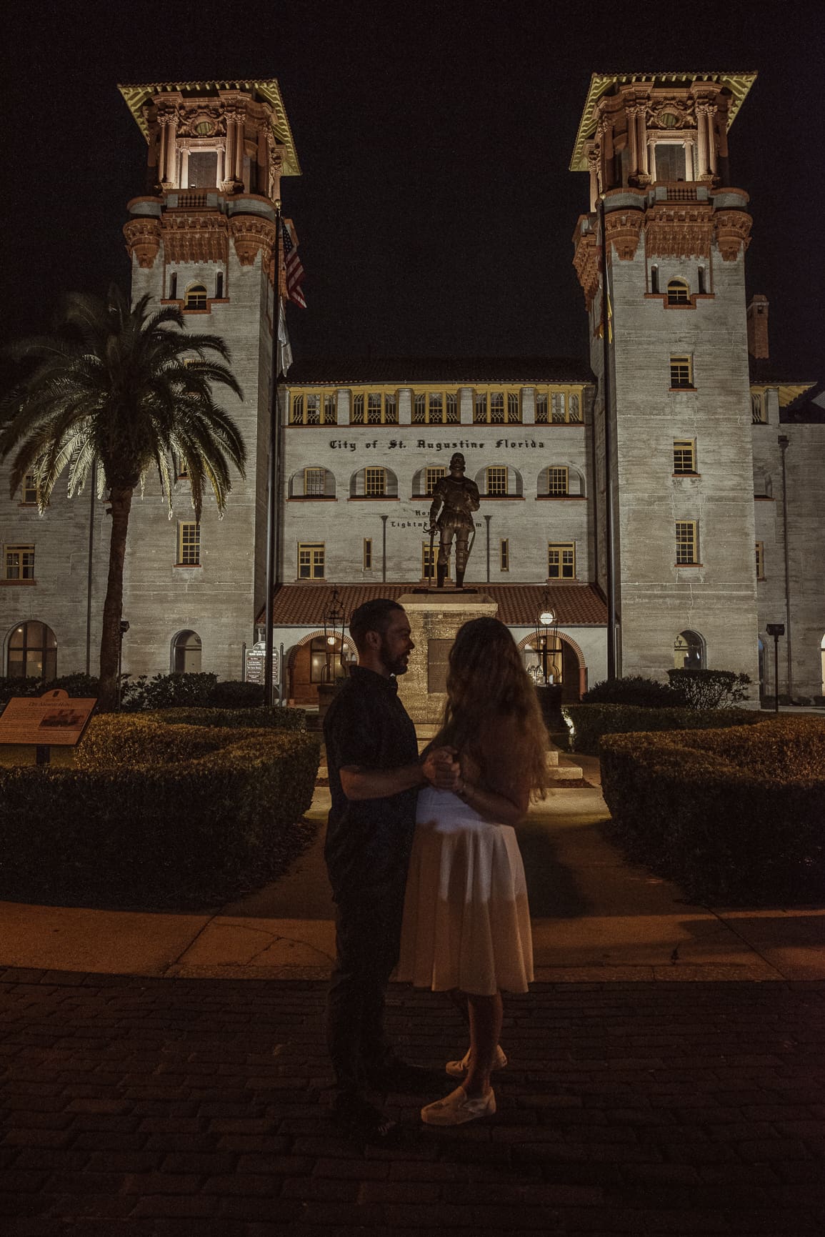 Romantic nighttime couple portrait in downtown St. Augustine in front of Lightner Museum.