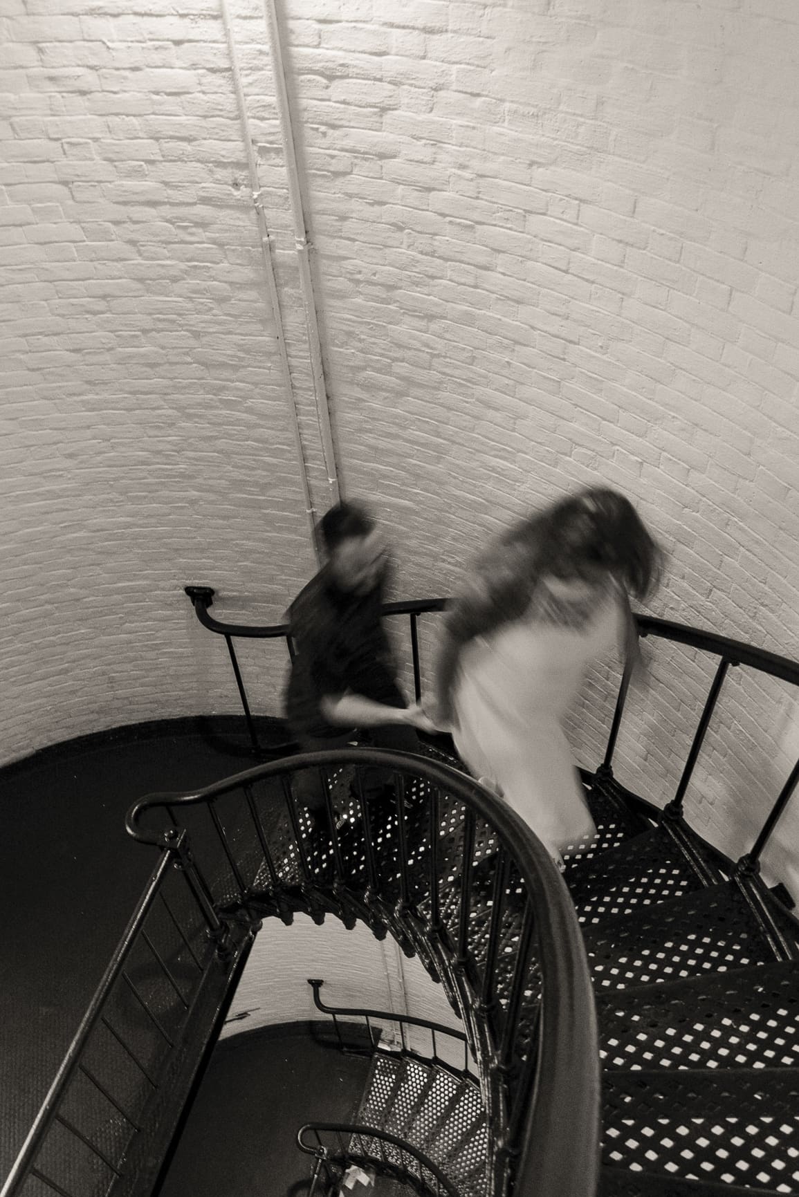 Couple walking down a historic spiral staircase during a stylish St Augustine engagement session photographed by a St Augustine wedding photographer