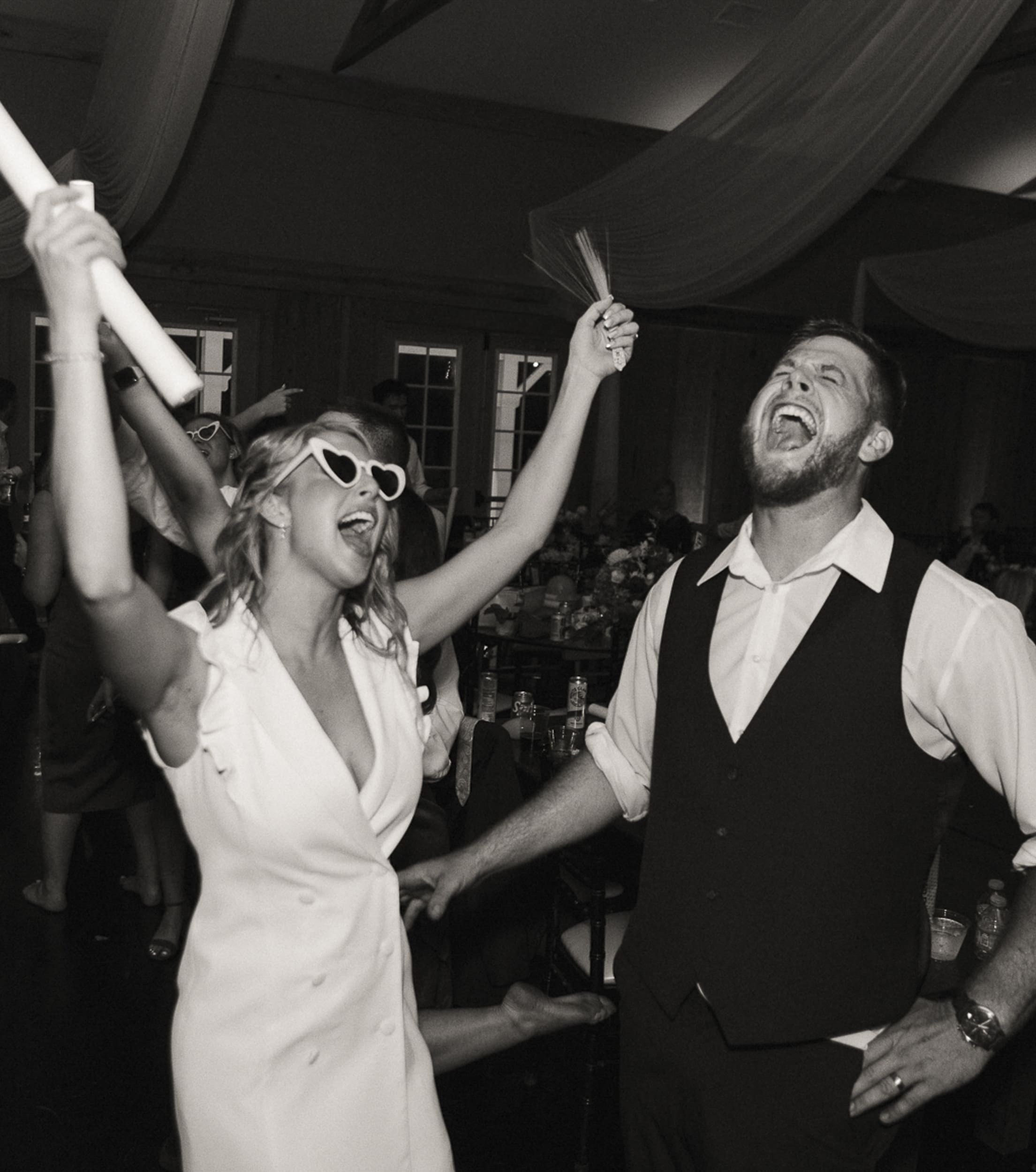 Bride and groom dancing energetically on the reception dance floor surrounded by friends and family. 