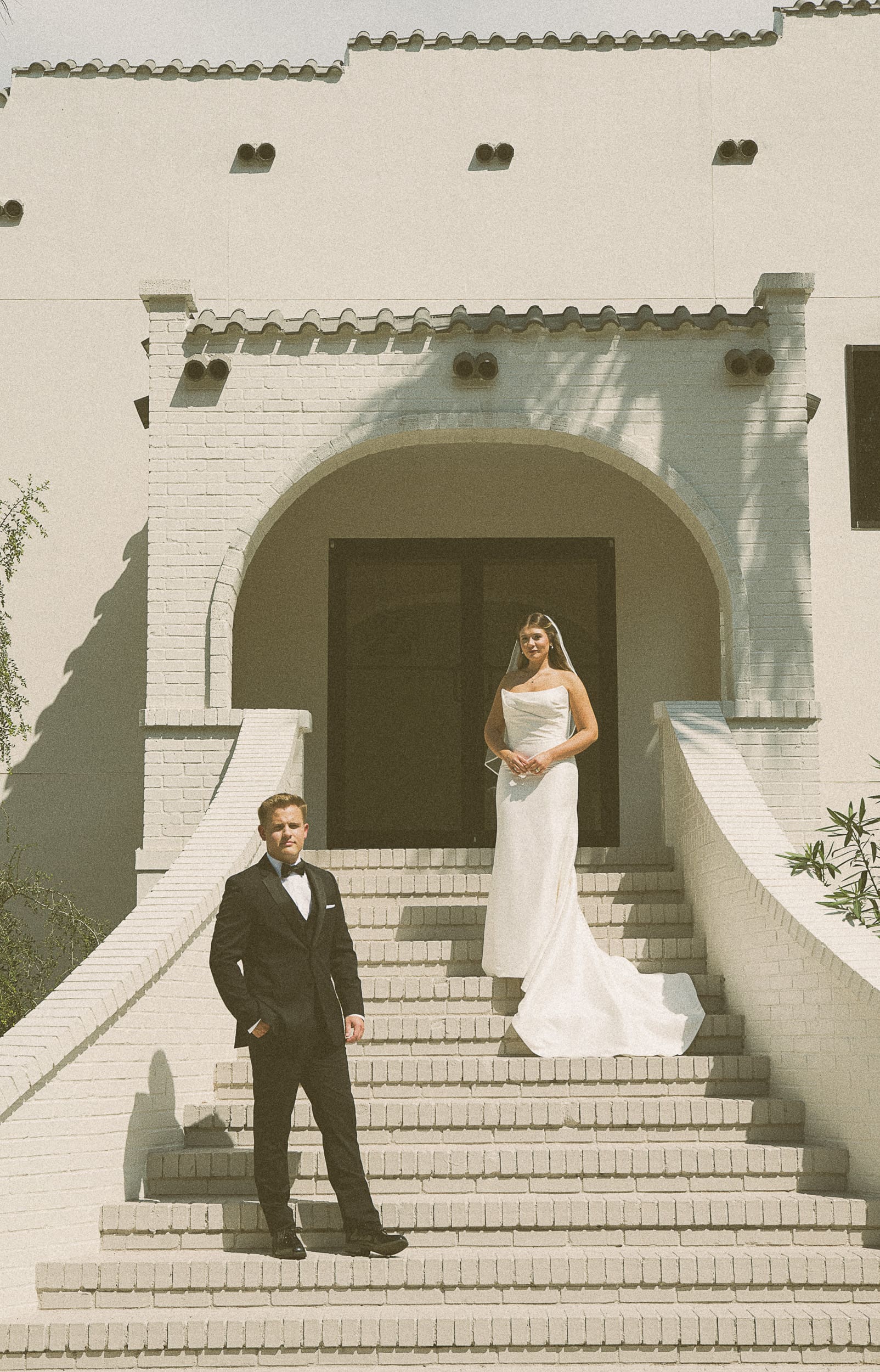 Editorial non traditional wedding portrait of bride and groom on white brick steps in St. Augustine, Florida, captured on film.