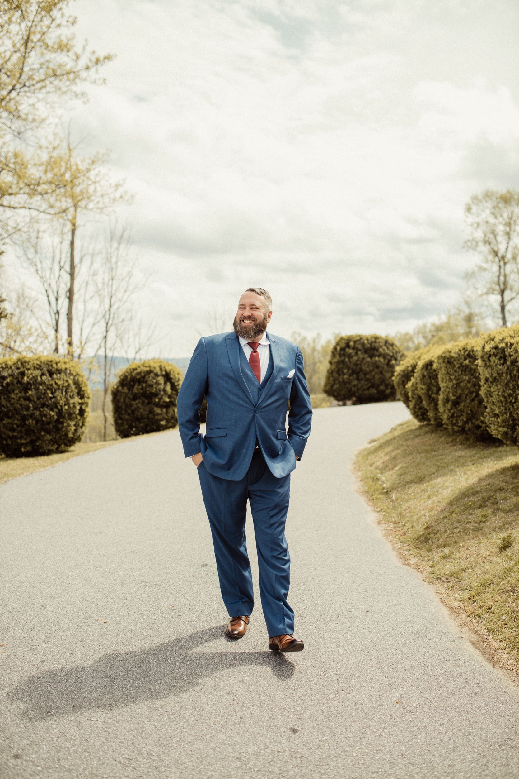 Groom walking along scenic mountain road during Blue Ridge wedding portraits. 
