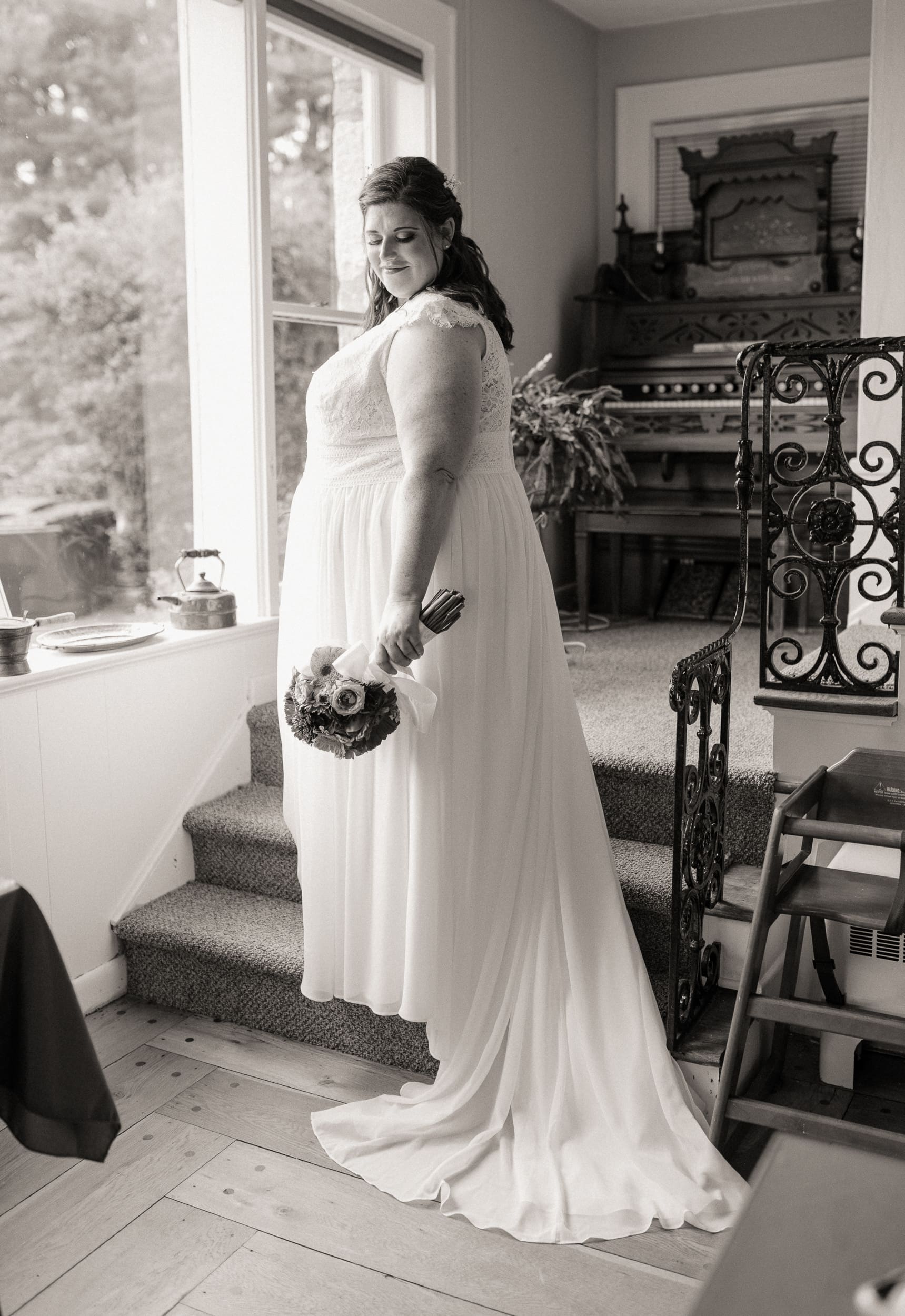 Bride standing in soft window light during intimate wedding bridal portrait.