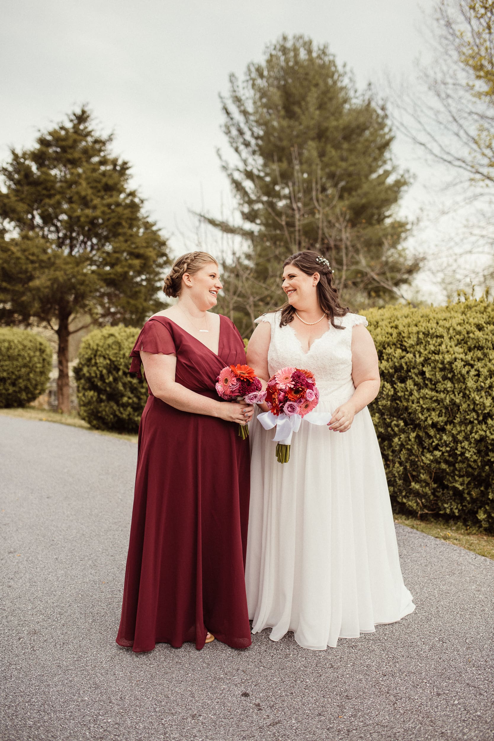Bride and bridesmaid holding bouquets during intimate North Carolina wedding portraits. 